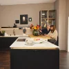 Una coppia è seduta in una cucina moderna con armadi scuri e fiori, Nolte Kitchen.