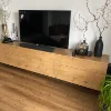 Soggiorno moderno con credenza in legno, decorata con vasi e piante, grande TV sopra. Nolte Living.