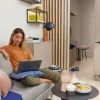 Una donna seduta su un divano in un salotto moderno con un laptop, circondata da decorazioni eleganti di Nolte Living.
