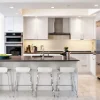 Cucina moderna con arredi bianchi e isola, attrezzata da Nolte Kitchen.