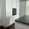 Cucina moderna bianca con forno integrato e pavimento in legno scuro, progettata da Nolte Kitchen.