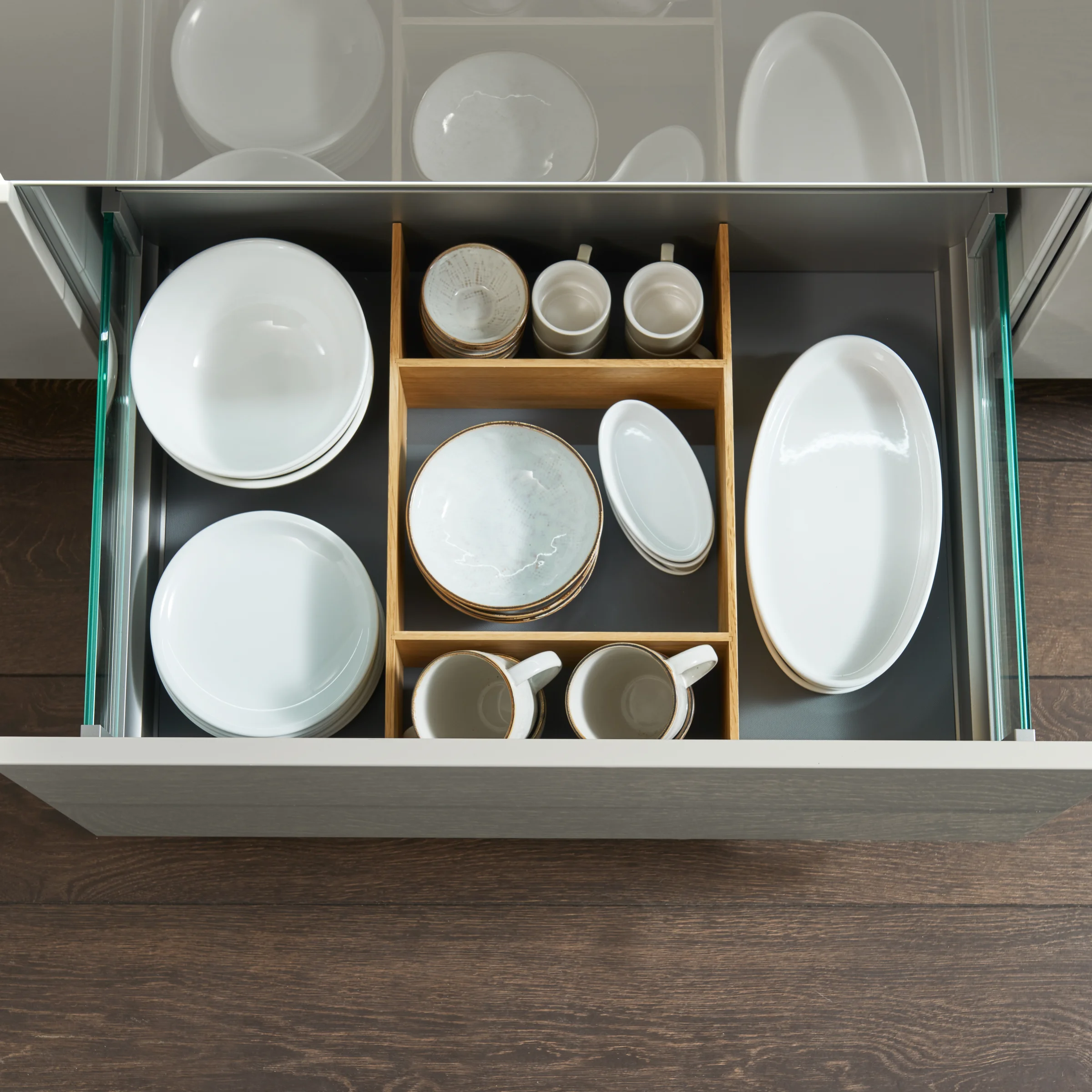 Cassetto da cucina aperto con stoviglie e divisori in legno, Nolte Kitchen.