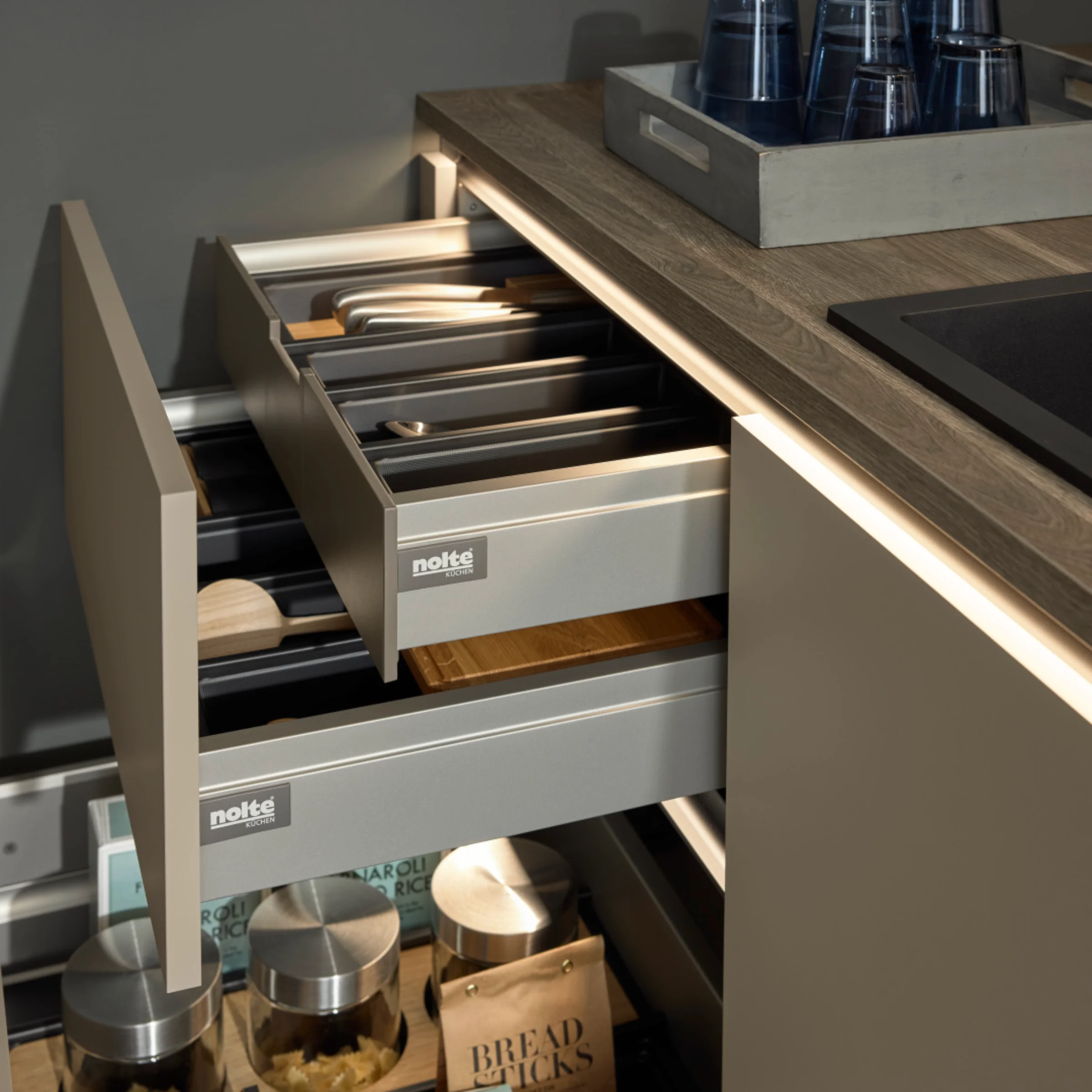 Cucina moderna con cassetti illuminati e piano in legno, design presentato da Nolte Kitchen.