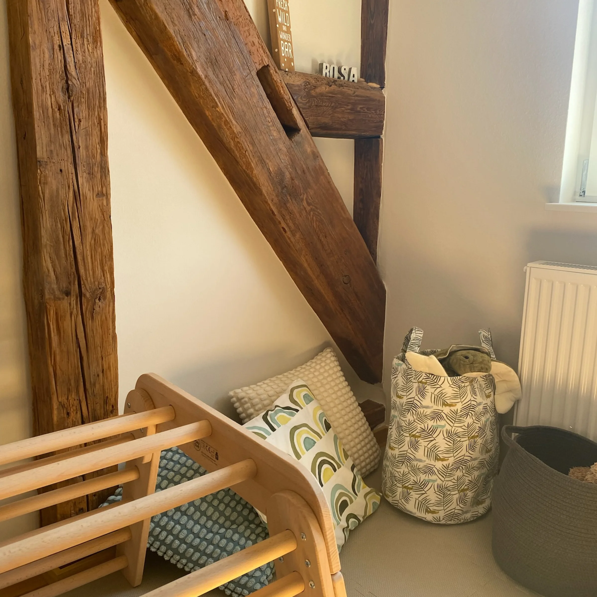 Una stanza accogliente con travi in legno, cuscini e cesti, mostra Nolte Living.