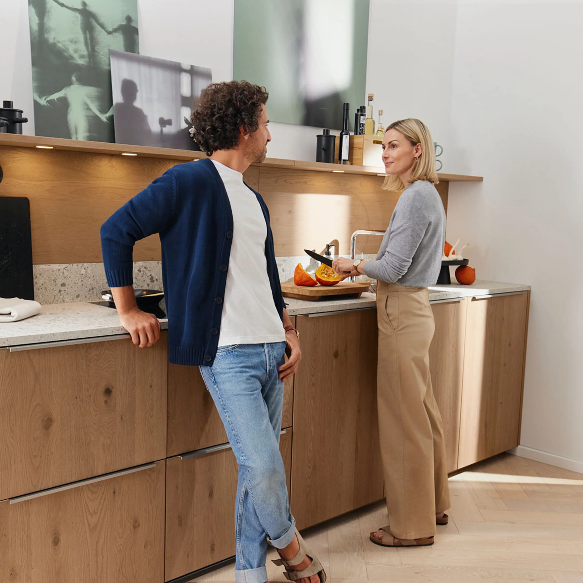 Un uomo e una donna conversano in una cucina moderna con armadi in legno di Nolte Kitchen.
