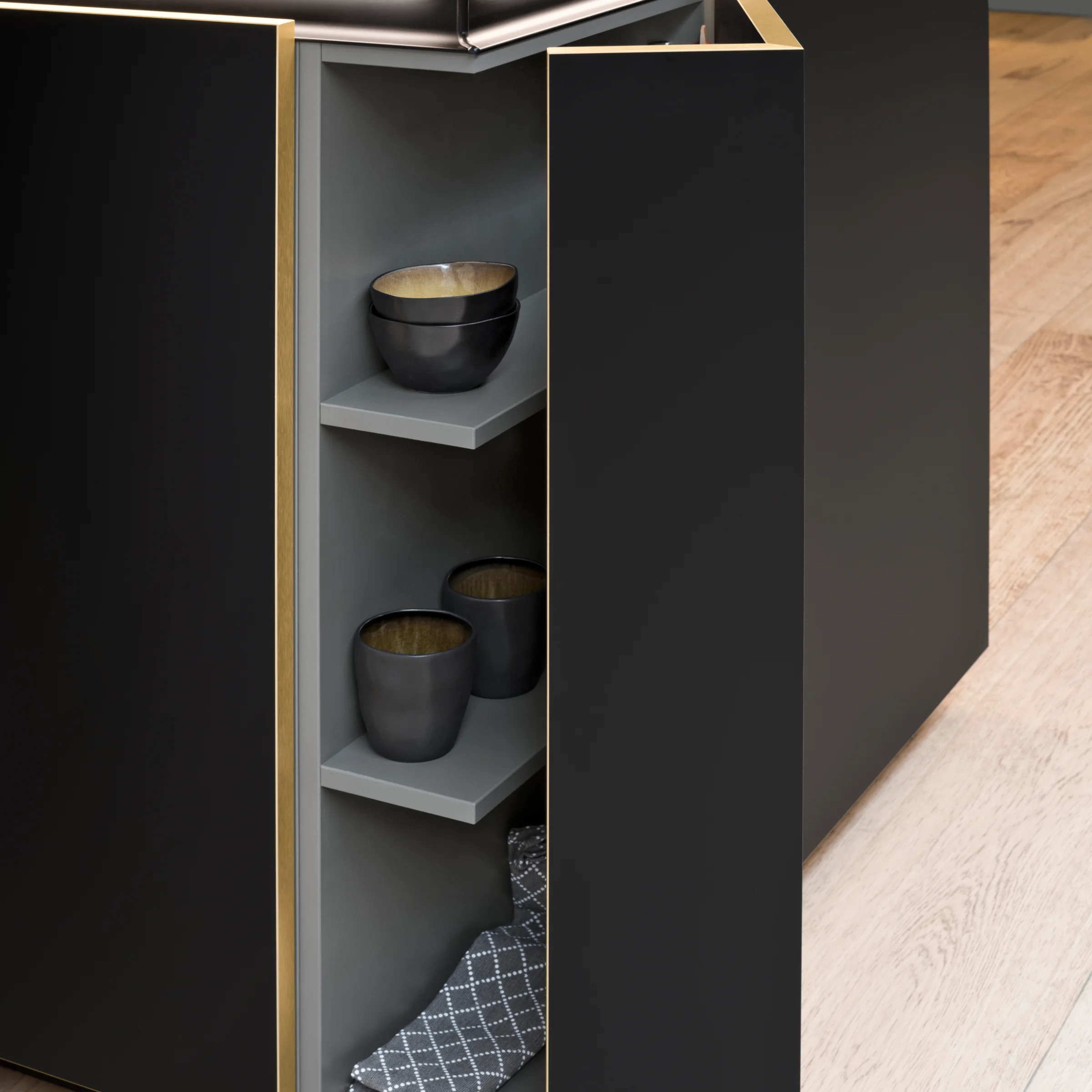 Cucina moderna nera con anta dell'armadio aperta e stoviglie, di Nolte Kitchen.