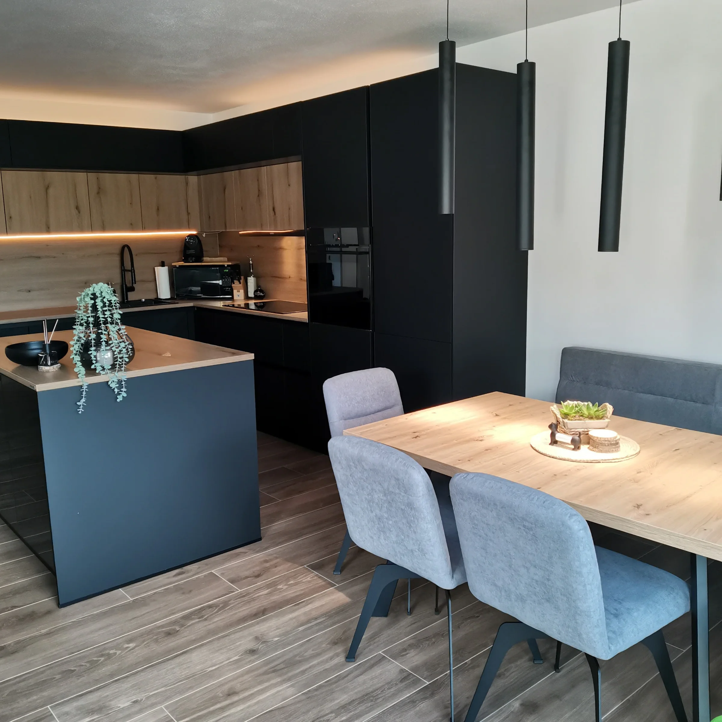 Cucina moderna con accenti in legno e nero, tavolo da pranzo e sedie, progettata da Nolte Kitchen.