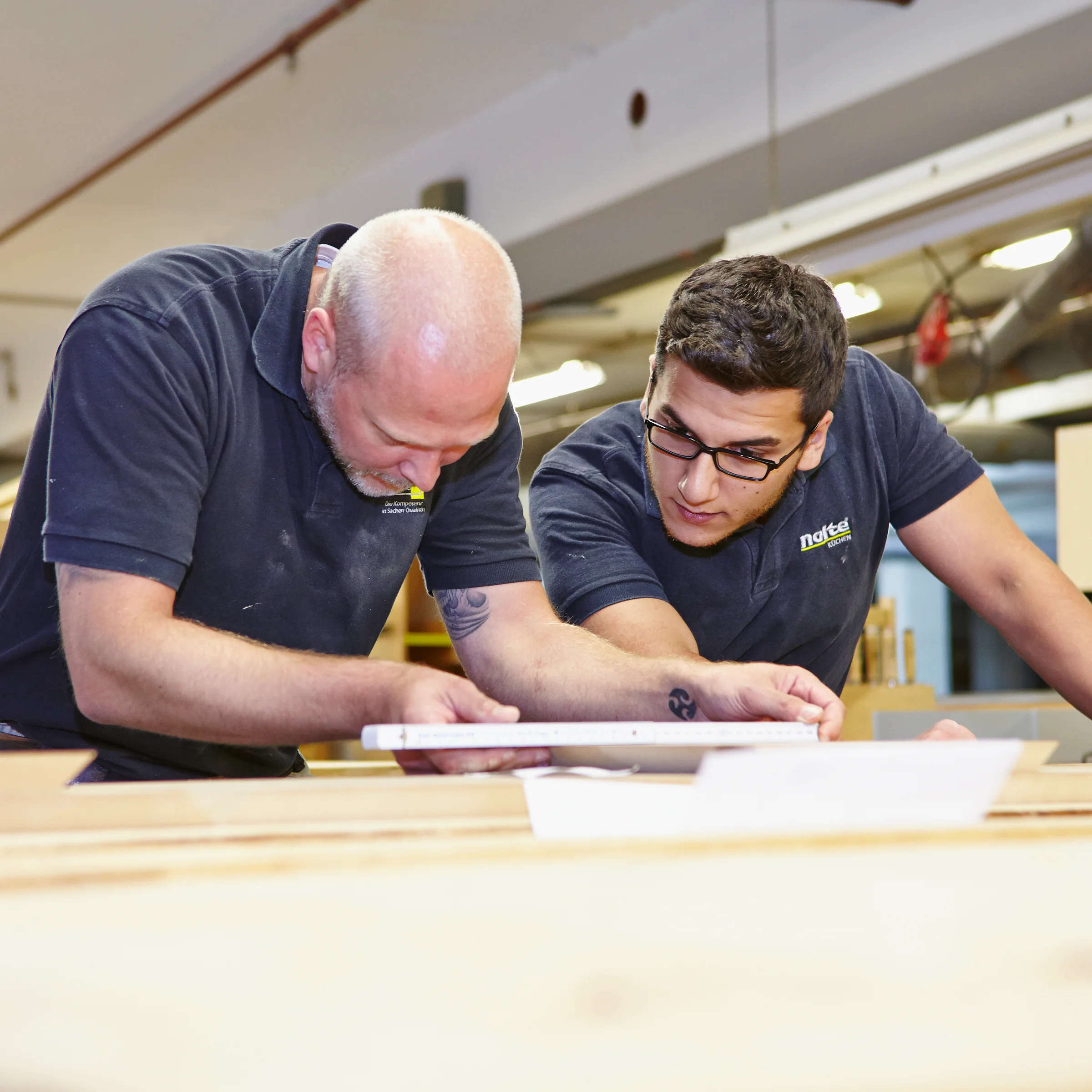 Due uomini lavorano insieme in un'officina su un progetto di legno per Nolte Kitchen.
