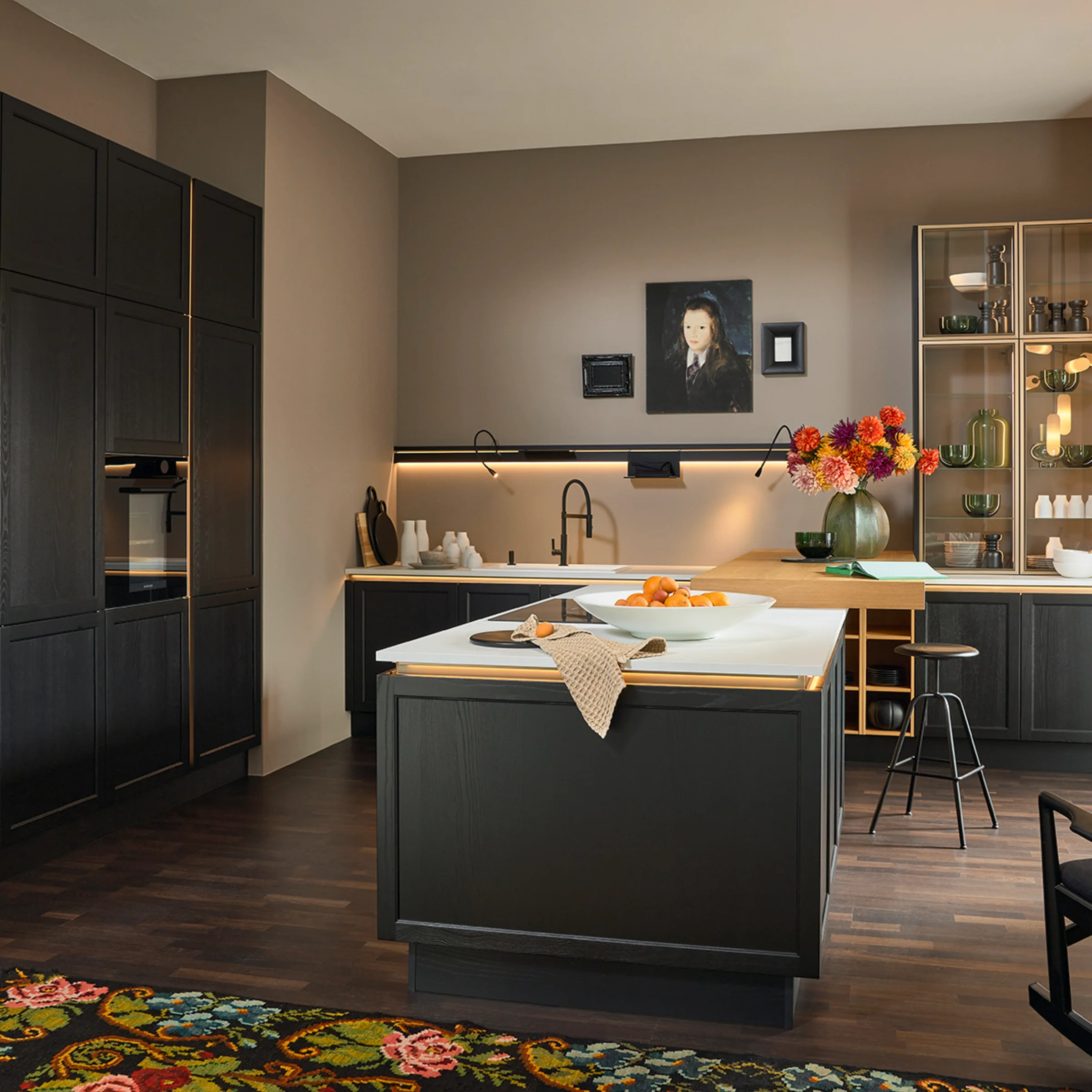 Cucina moderna con armadi scuri e isola; scaffali decorativi sullo sfondo. Nolte Kitchen.