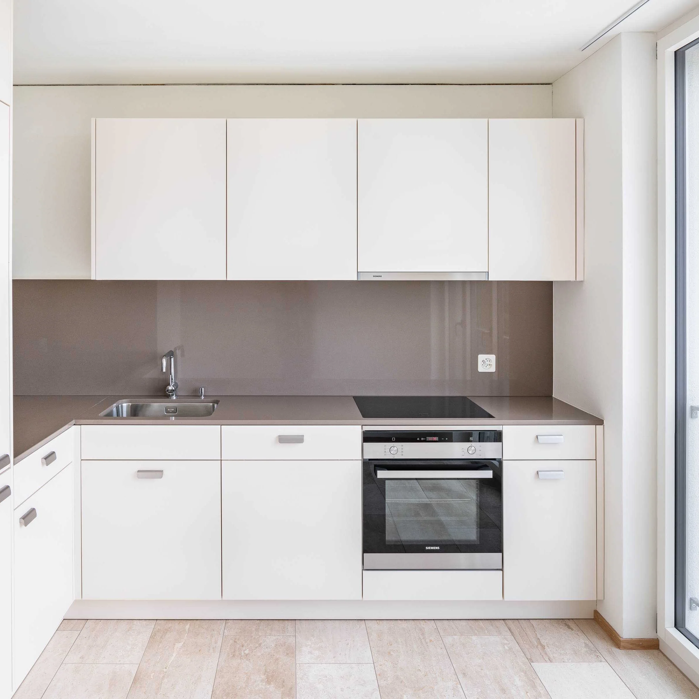 Modern kitchen with white cabinets and built-in appliances, designed by Nolte Kitchen.