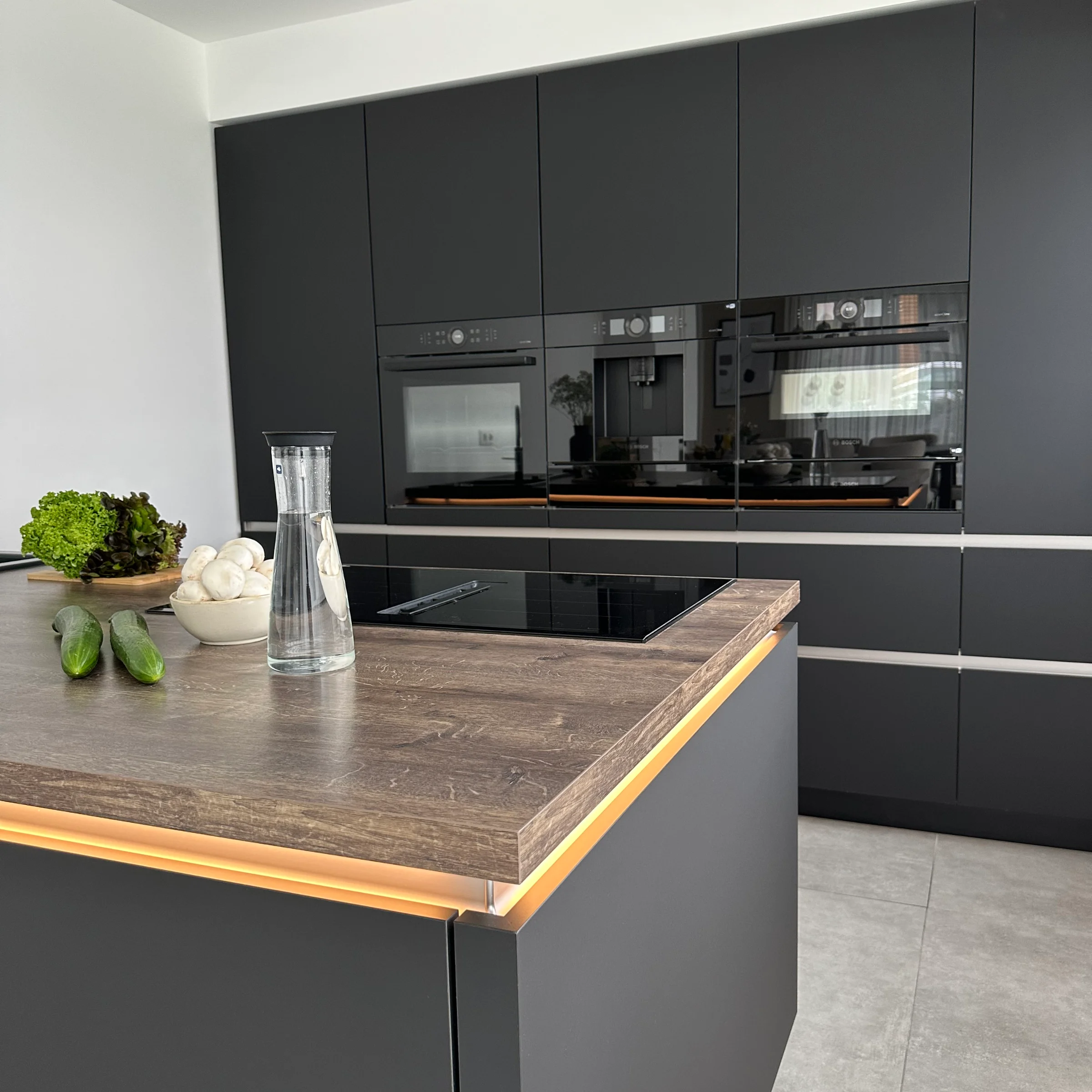 Cucina moderna con armadi scuri e isola, elegantemente progettata da Nolte Kitchen.