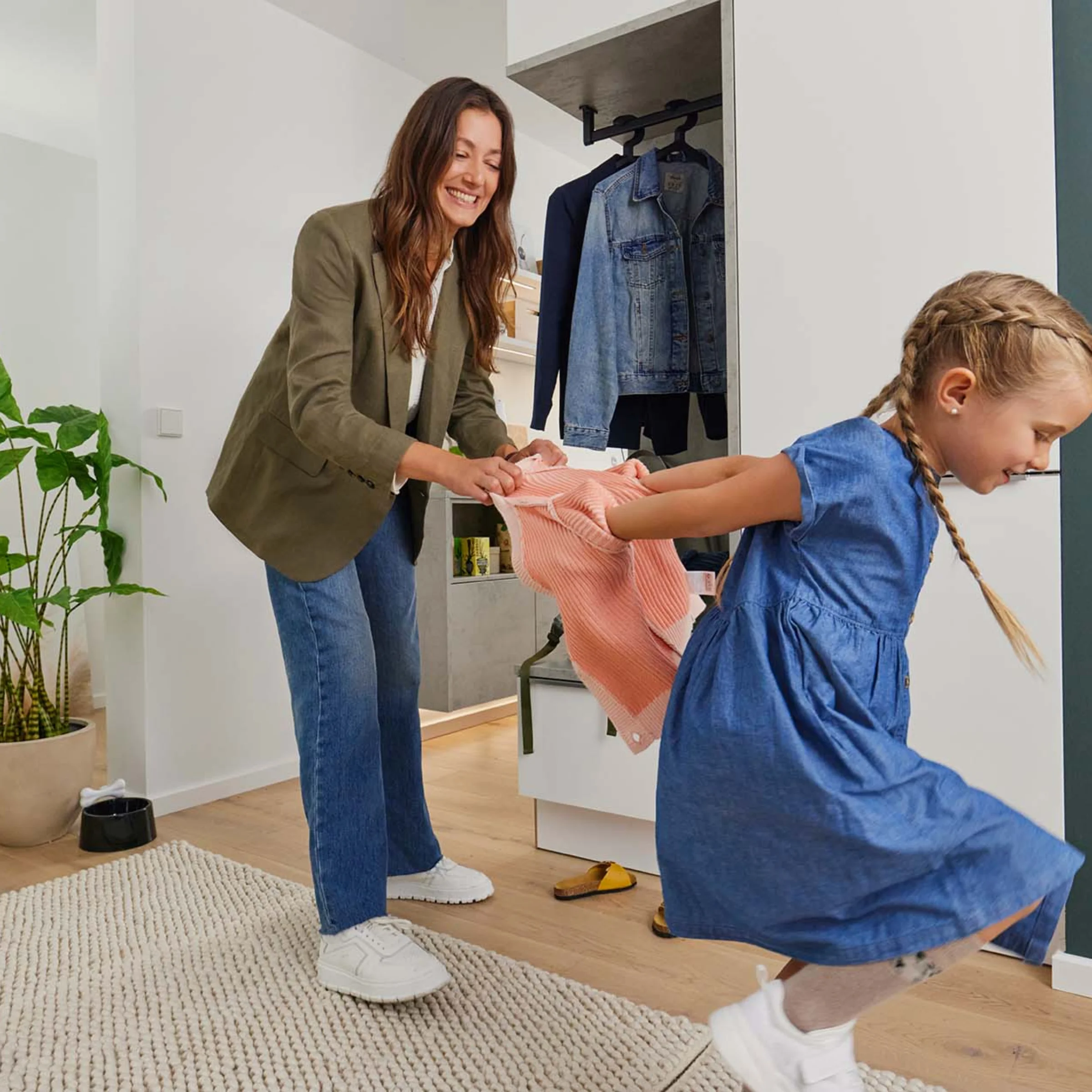 Una donna aiuta un bambino che gioca in un soggiorno moderno con mobili Nolte Living.