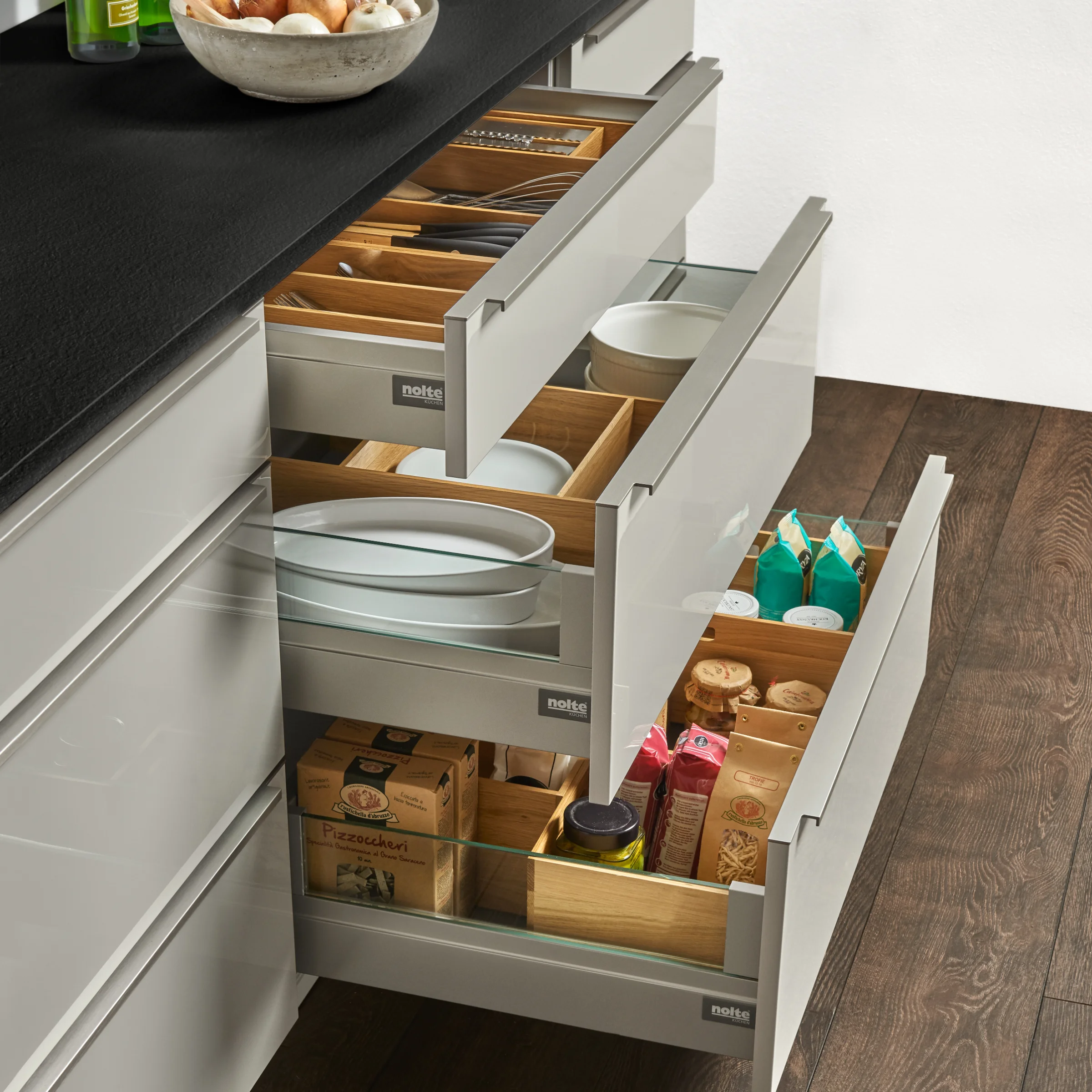 Cucina moderna con cassetti aperti pieni di utensili di Nolte Kitchen.