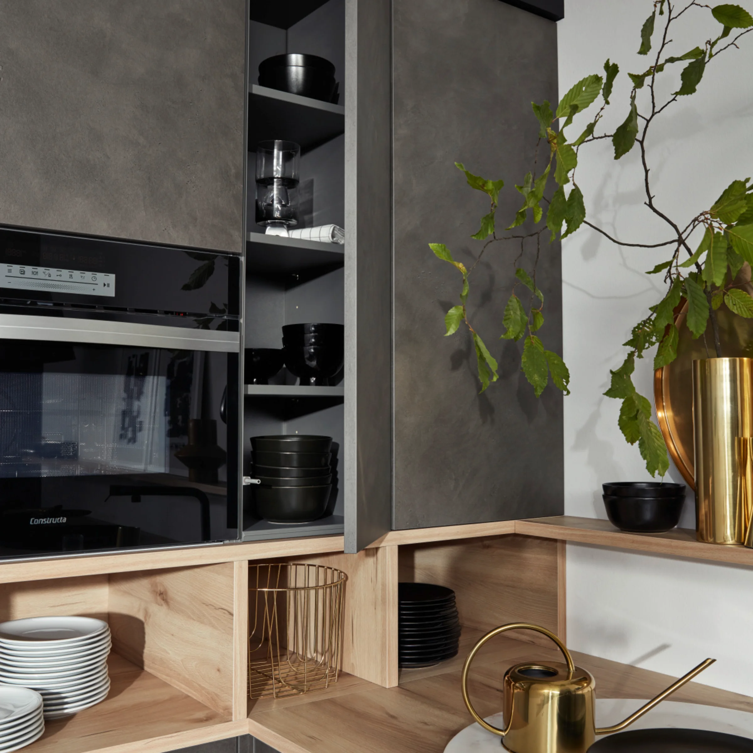 Cucina moderna con armadi grigi e dettagli in legno, decorata con piante. Nolte Kitchen.