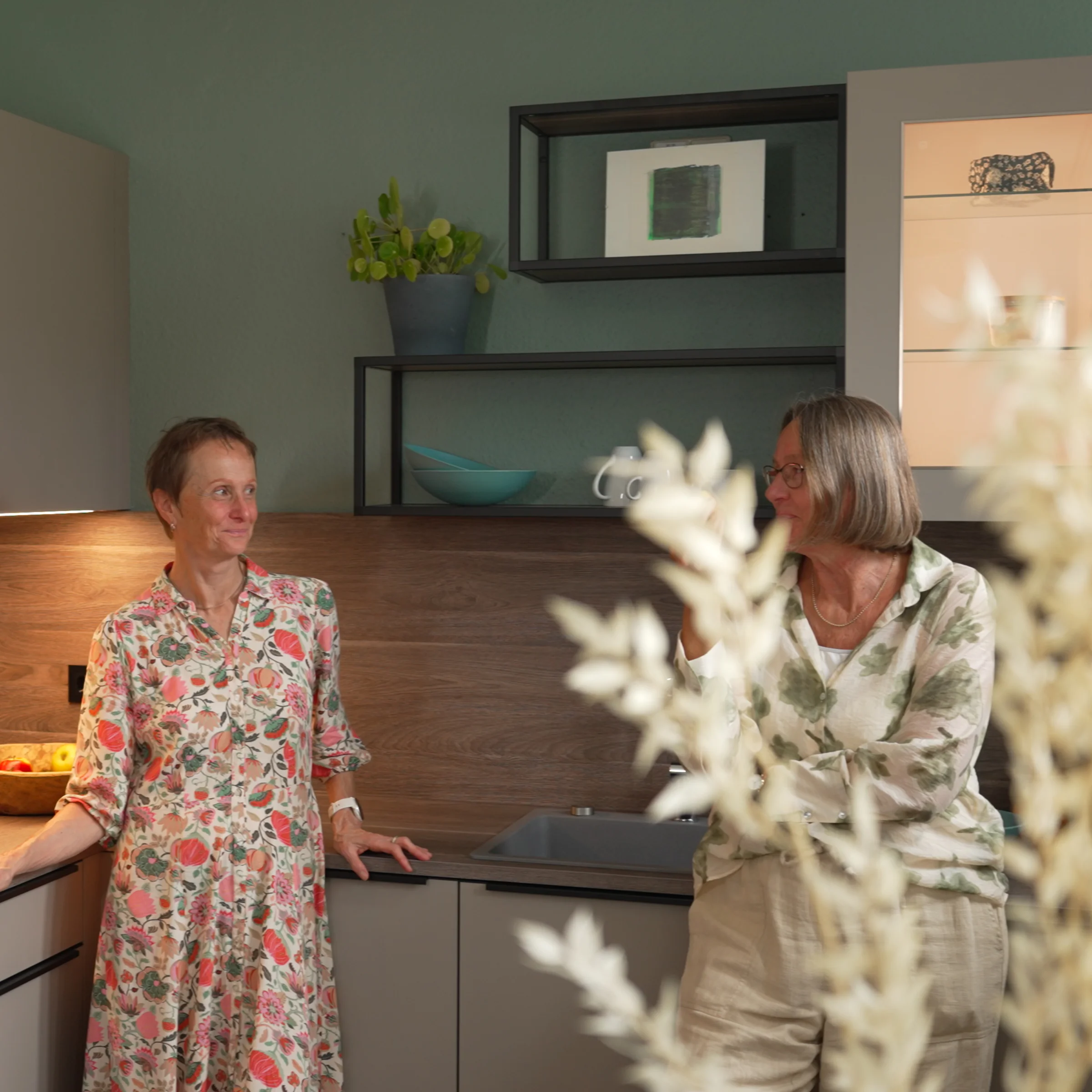 Una cucina moderna effetto legno con tre persone, presentata da Nolte Kitchen.