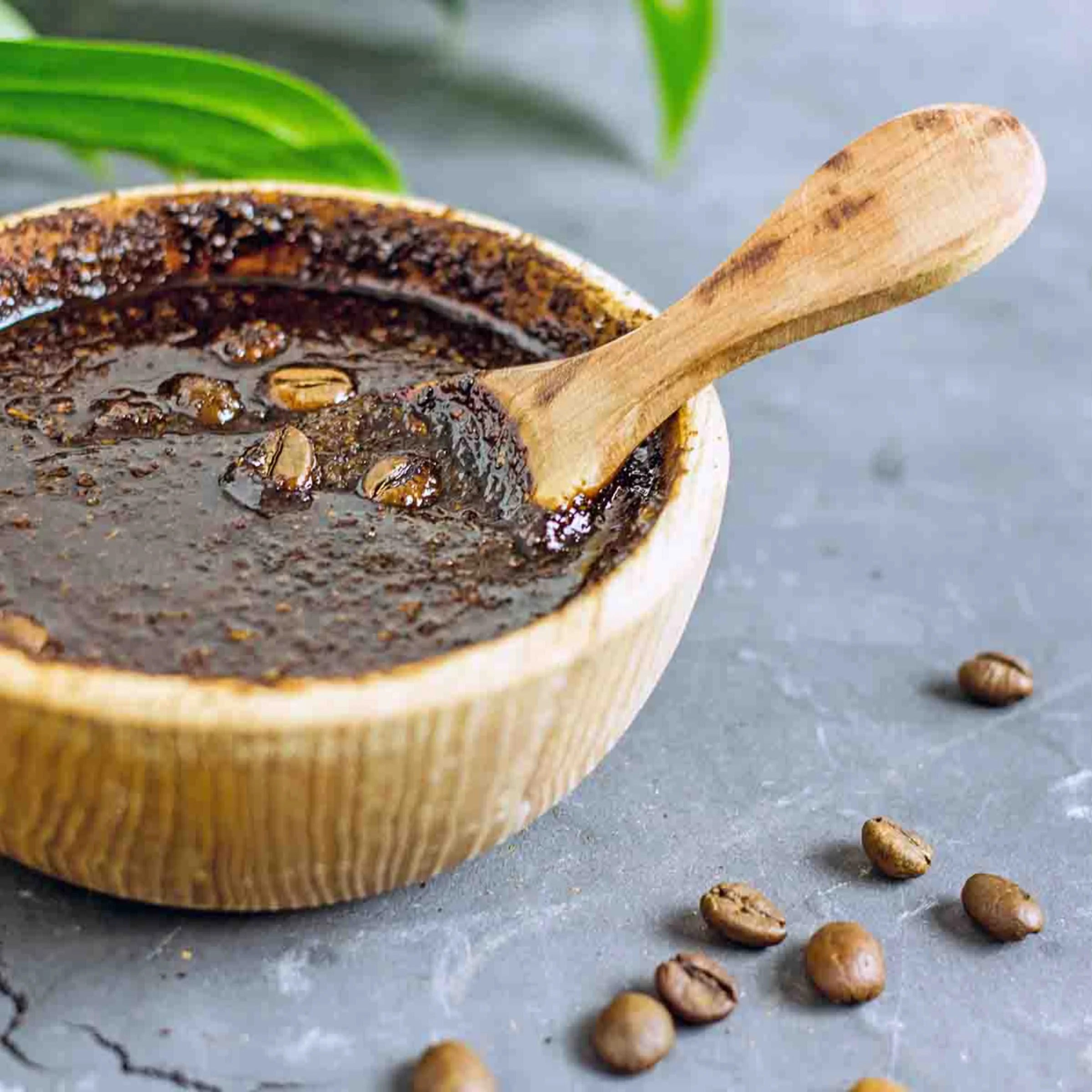 Ciotola con scrub al caffè e chicchi di caffè su sfondo grigio.