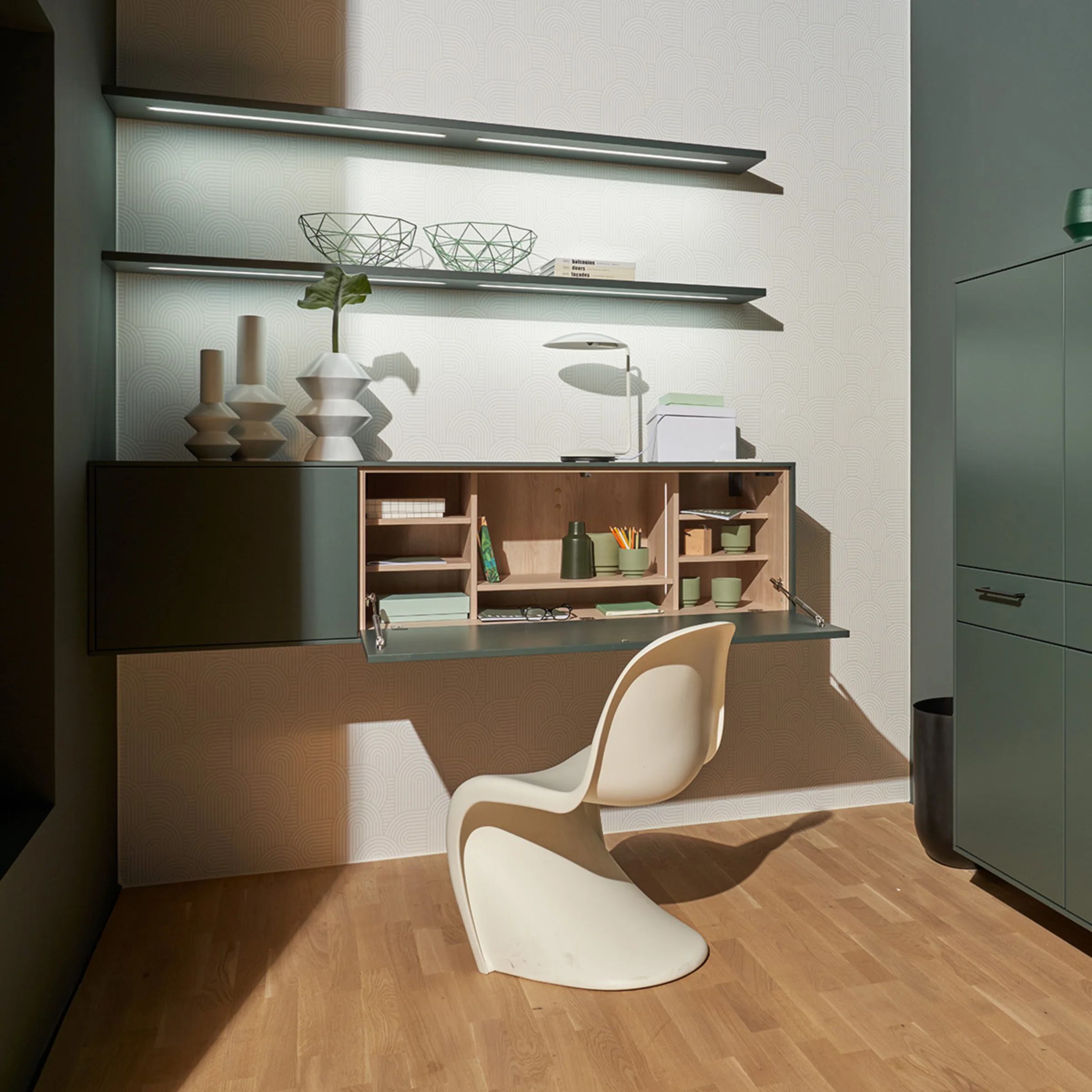 Un elegante spazio di lavoro con armadio e scaffale verde di Nolte Living.