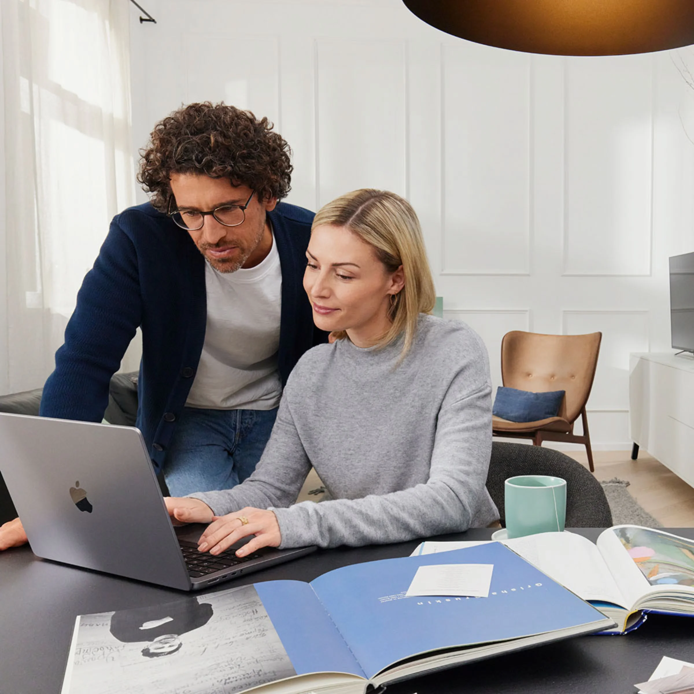 Una coppia lavora insieme su un laptop in un soggiorno moderno con arredamento Nolte Living.