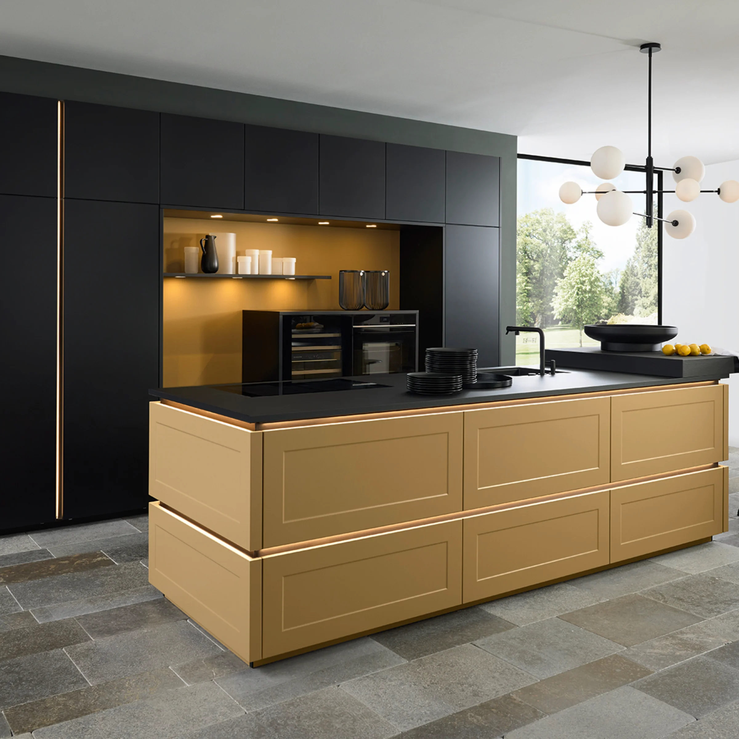 Cucina moderna con isola dorata e armadi neri, illuminata da una lampada a sospensione. Nolte Kitchen.