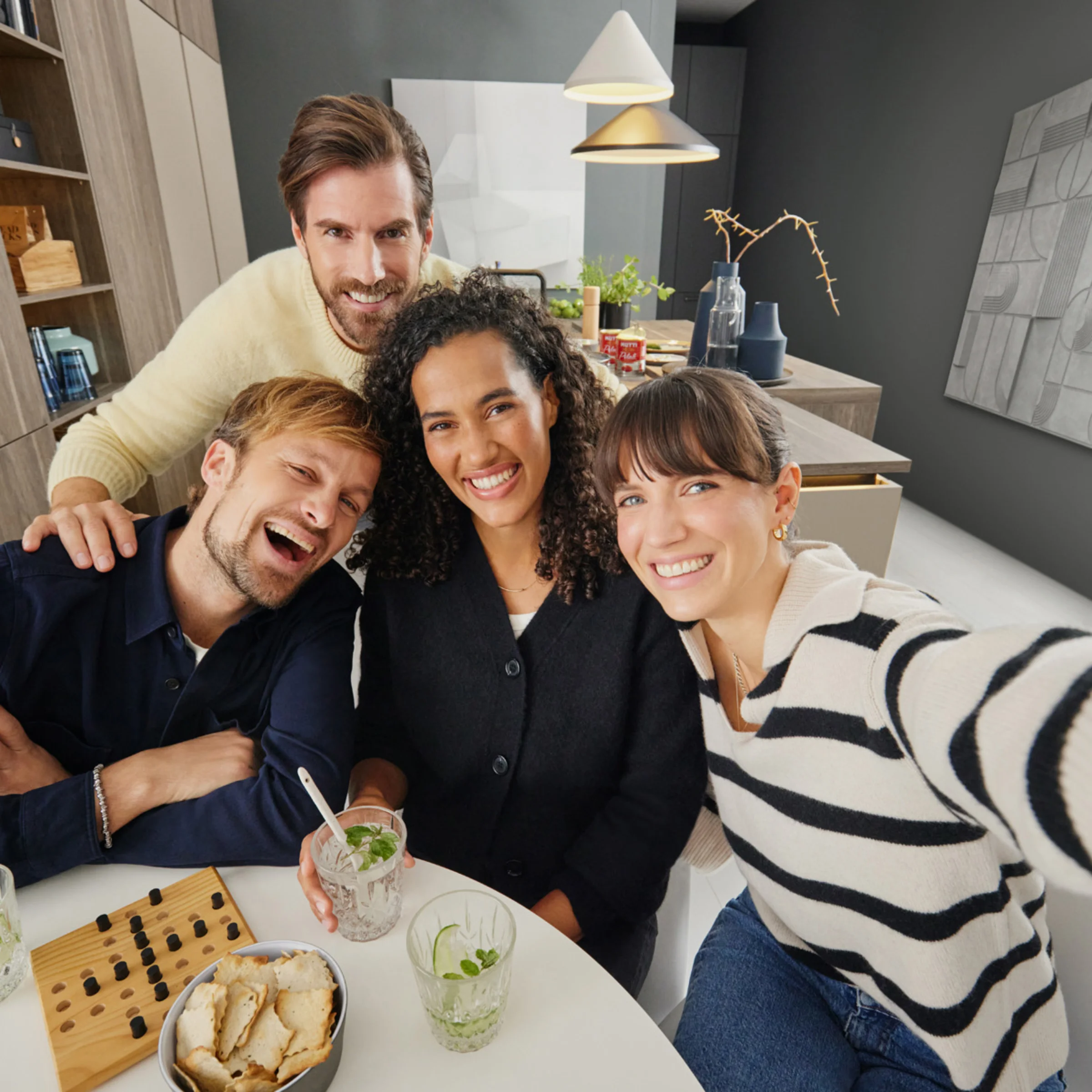 Un gruppo di persone sorride seduto in una cucina moderna. Nolte Kitchen.