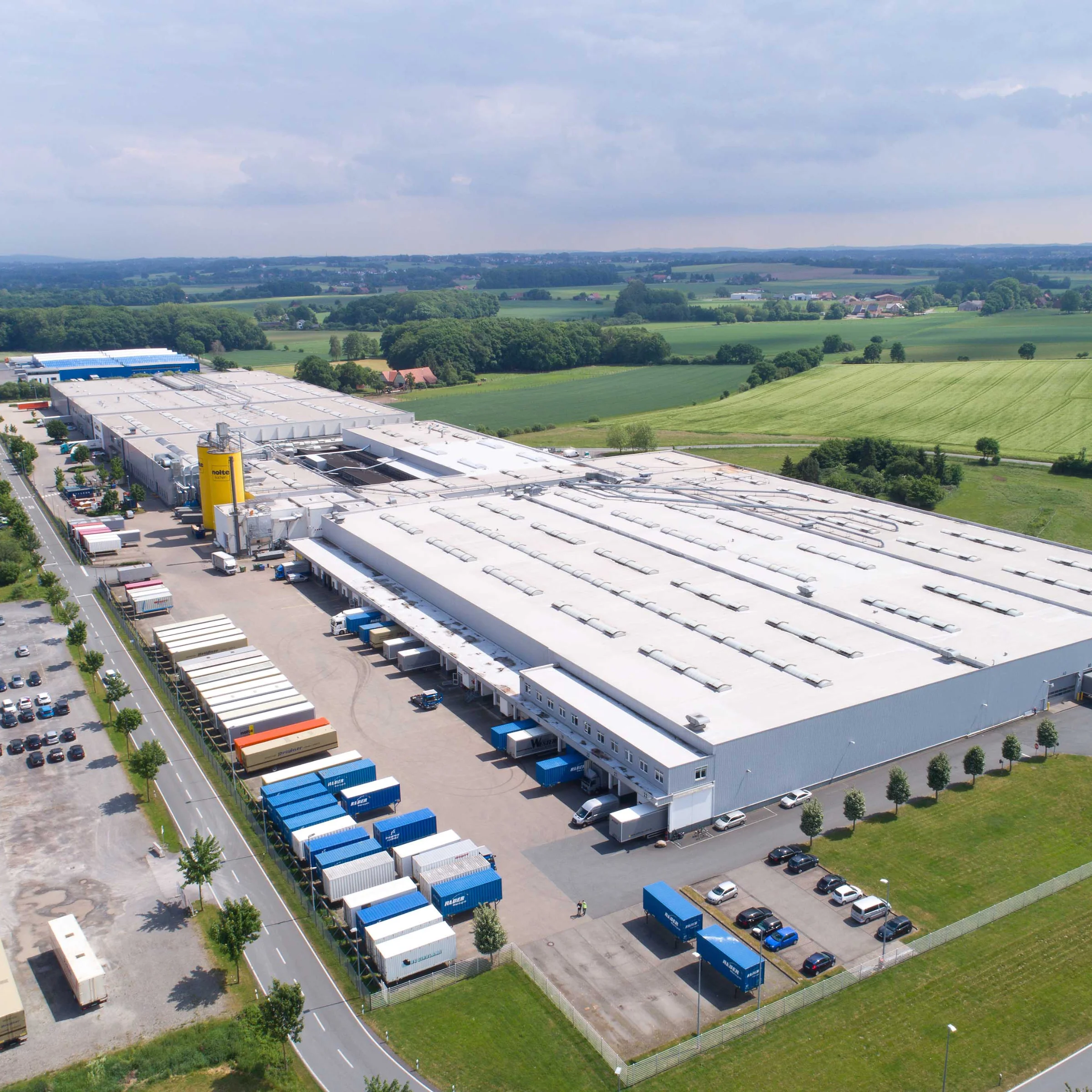 Grande stabilimento industriale in campagna, circondato da campi; Nolte Kitchen.