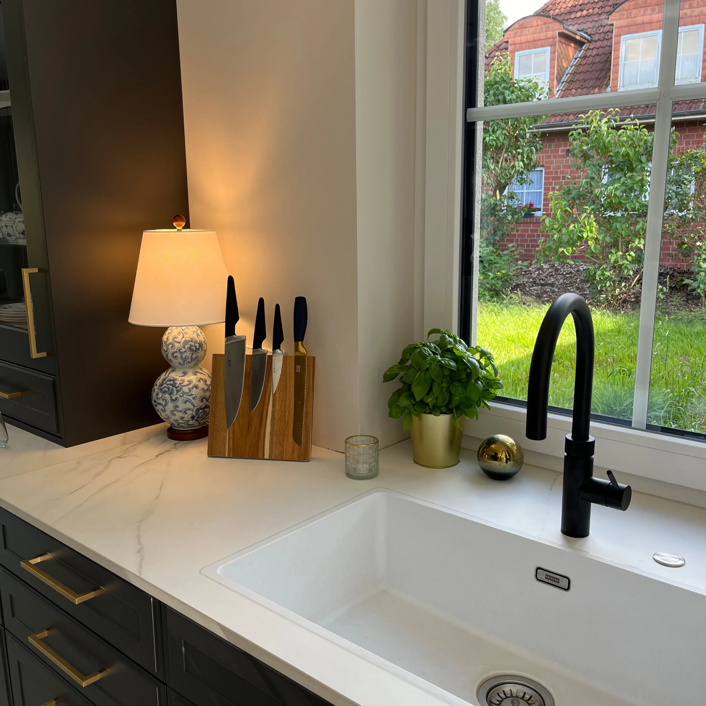 Modern kitchen with white sink and herb pot on countertop, designed by Nolte Kitchen.