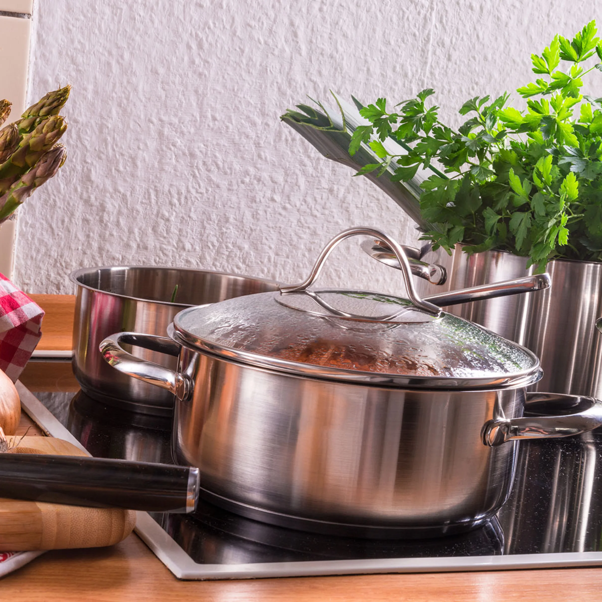 Ingredienti freschi e pentole su un piano cottura in una cucina moderna di Nolte Kitchen.