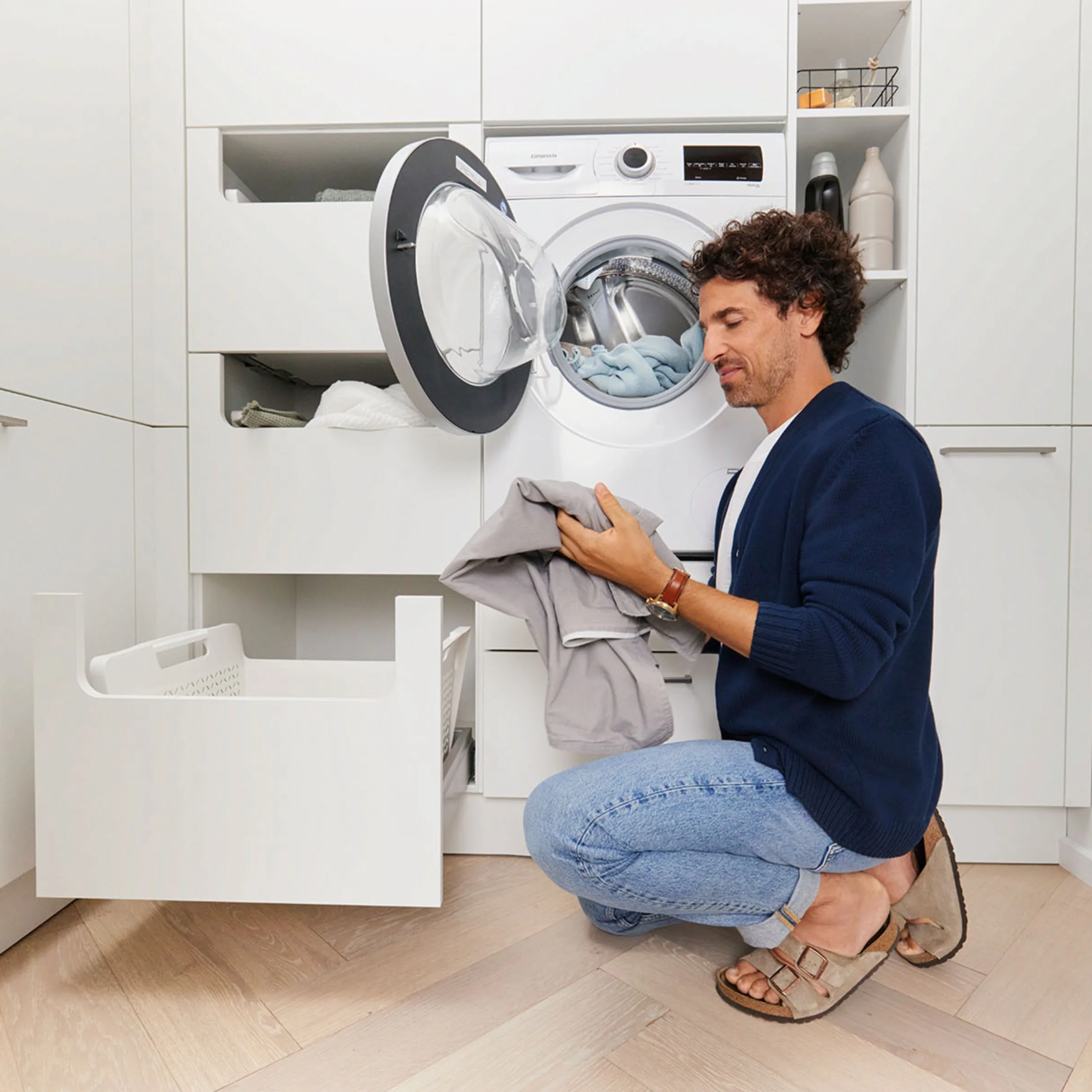 Ein Mann bedient eine Waschmaschine in einem modernen Nolte-Hauswirtschaftsraum.