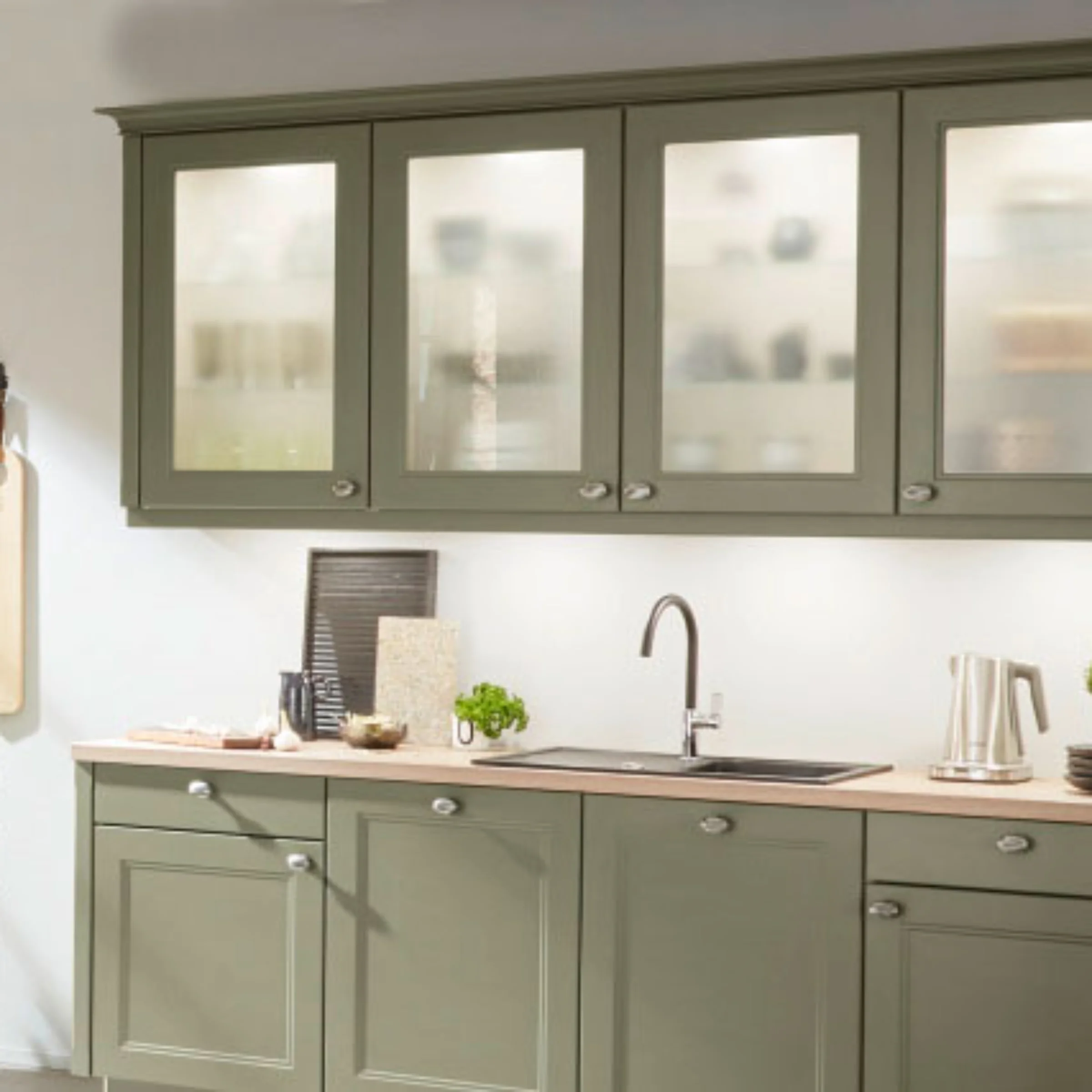 Una cucina moderna con armadi verdi e decorazioni. Nolte Kitchen.