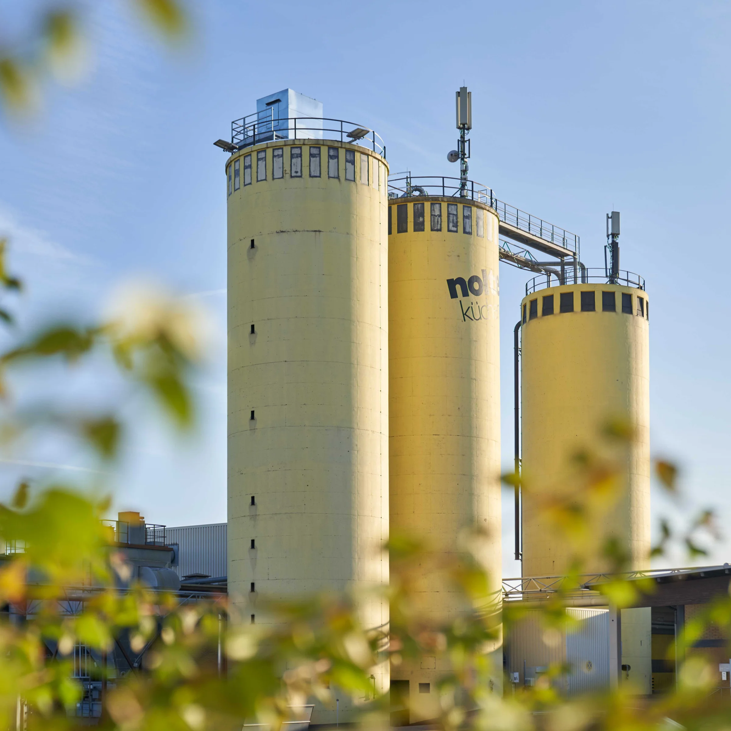 Tre grandi silos gialli con la scritta "Nolte Kitchen" davanti a un cielo limpido.