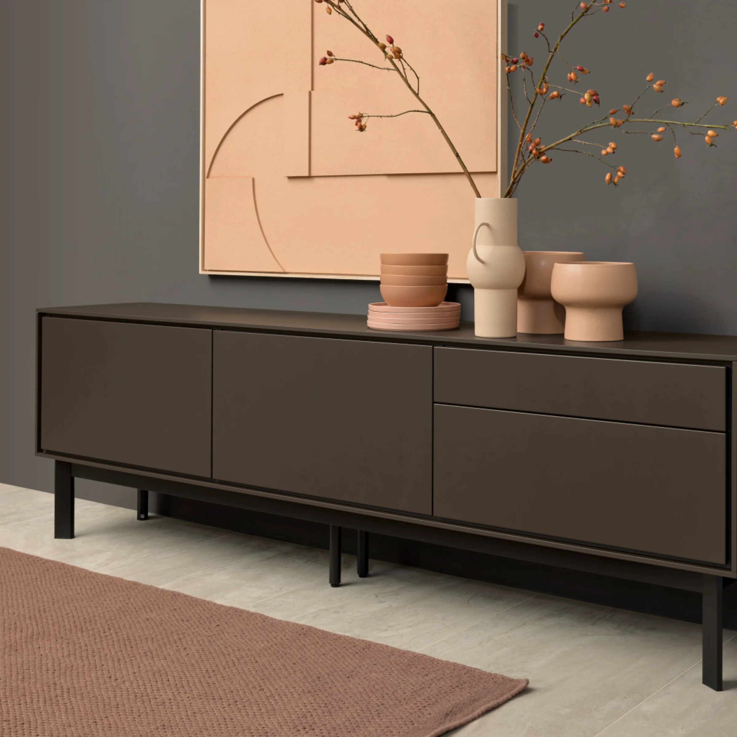 Elegante credenza con decorazioni davanti a una parete grigia, parte della collezione Nolte Living.