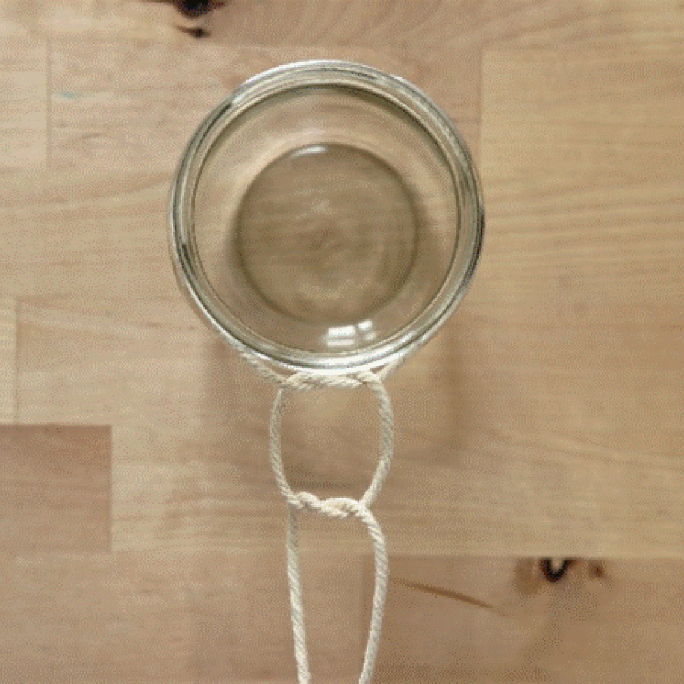 A glass tied with a rope to a hanging container.