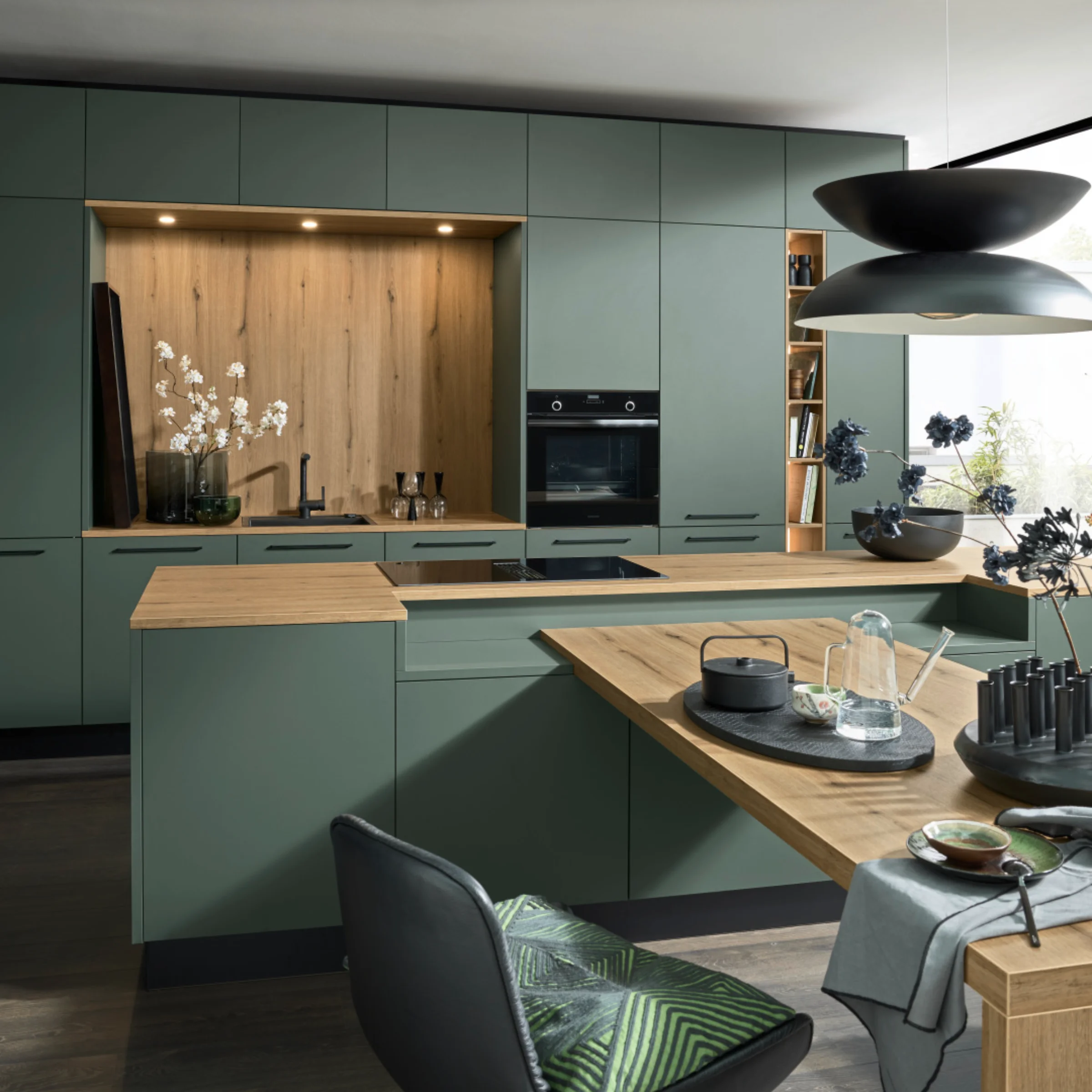 Una cucina moderna verde con accenti in legno e illuminazione elegante. Nolte Kitchen.