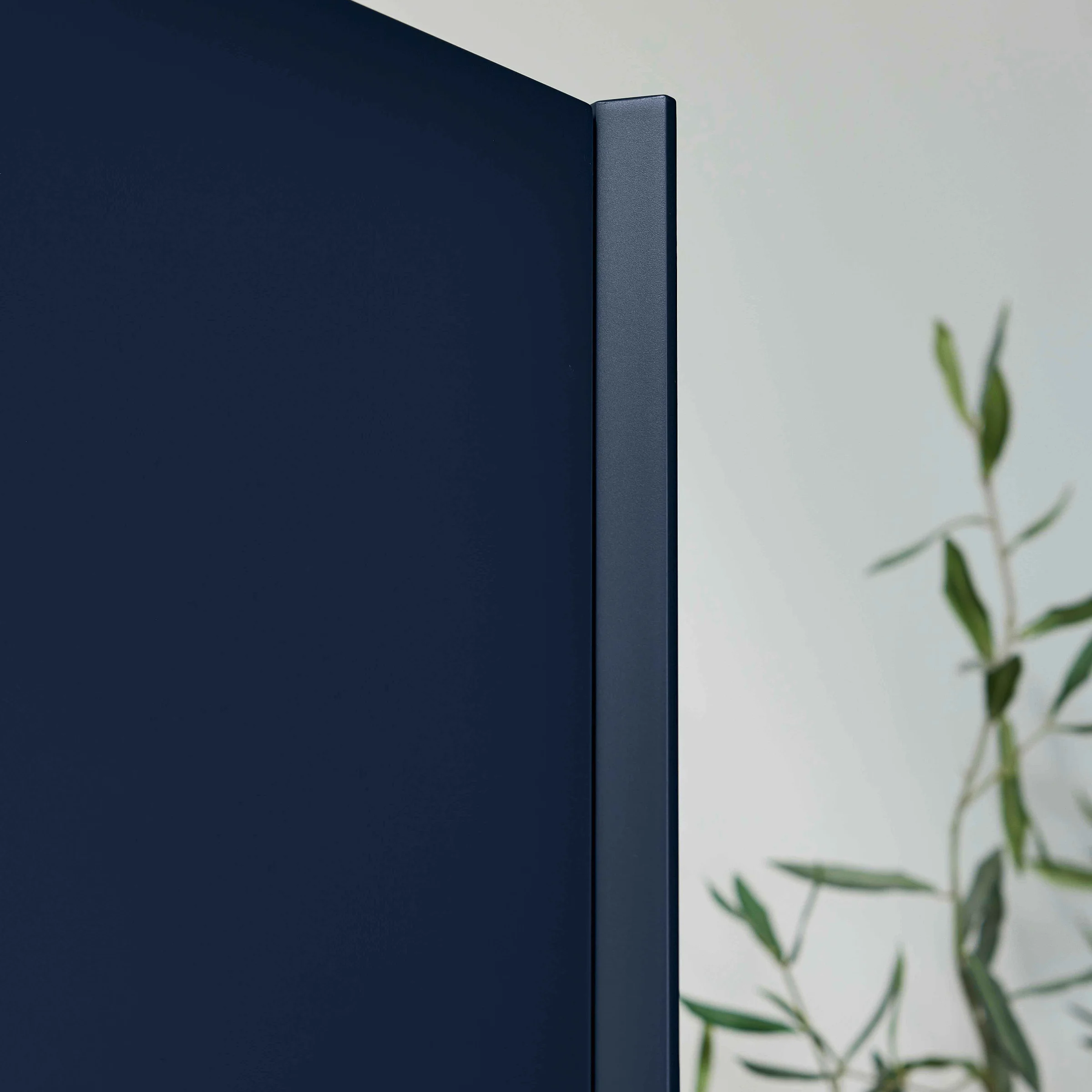 Porta blu di un armadio con pianta sullo sfondo, design moderno di Nolte Kitchen.