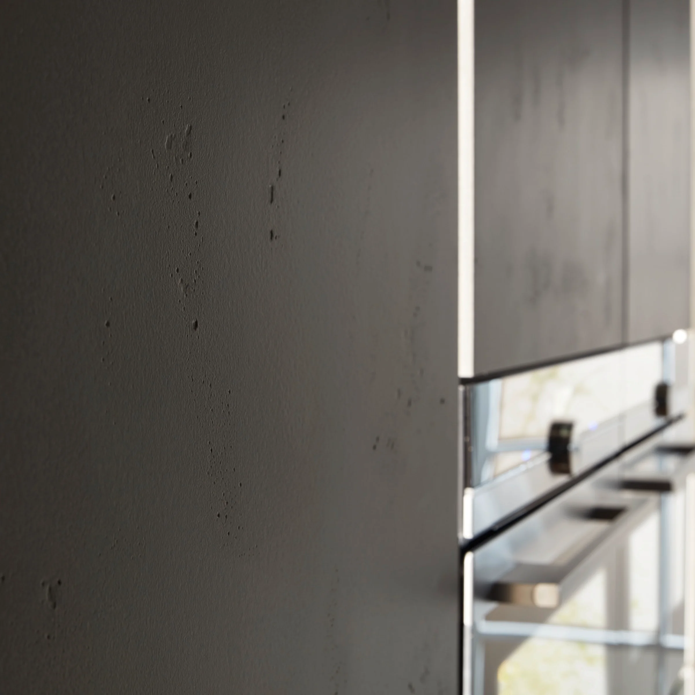 Cucina moderna con armadi scuri e elettrodomestici in acciaio inox, progettata da Nolte Kitchen.