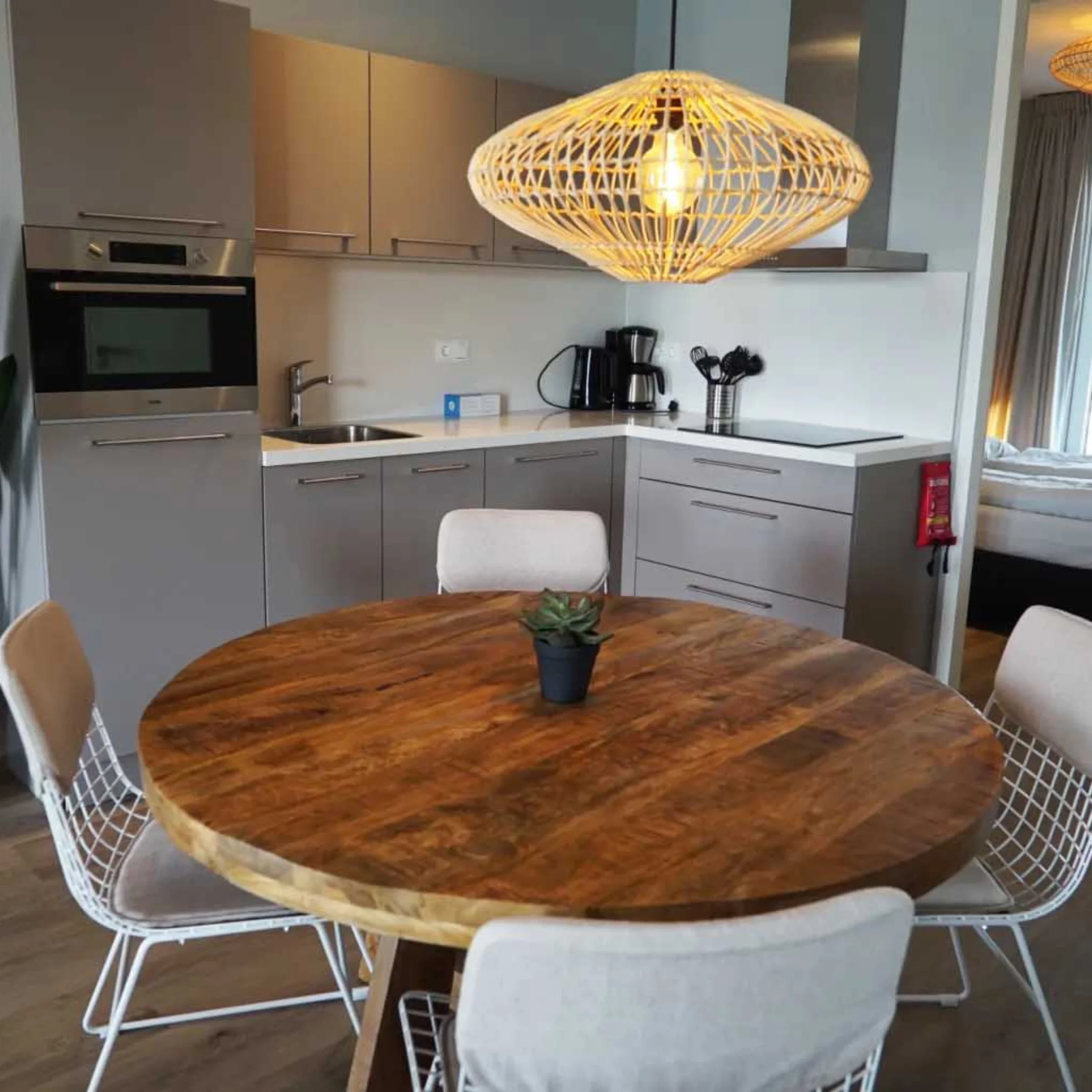 Cucina moderna con tavolo rotondo in legno e lampada a sospensione, sullo sfondo cucine Nolte.
