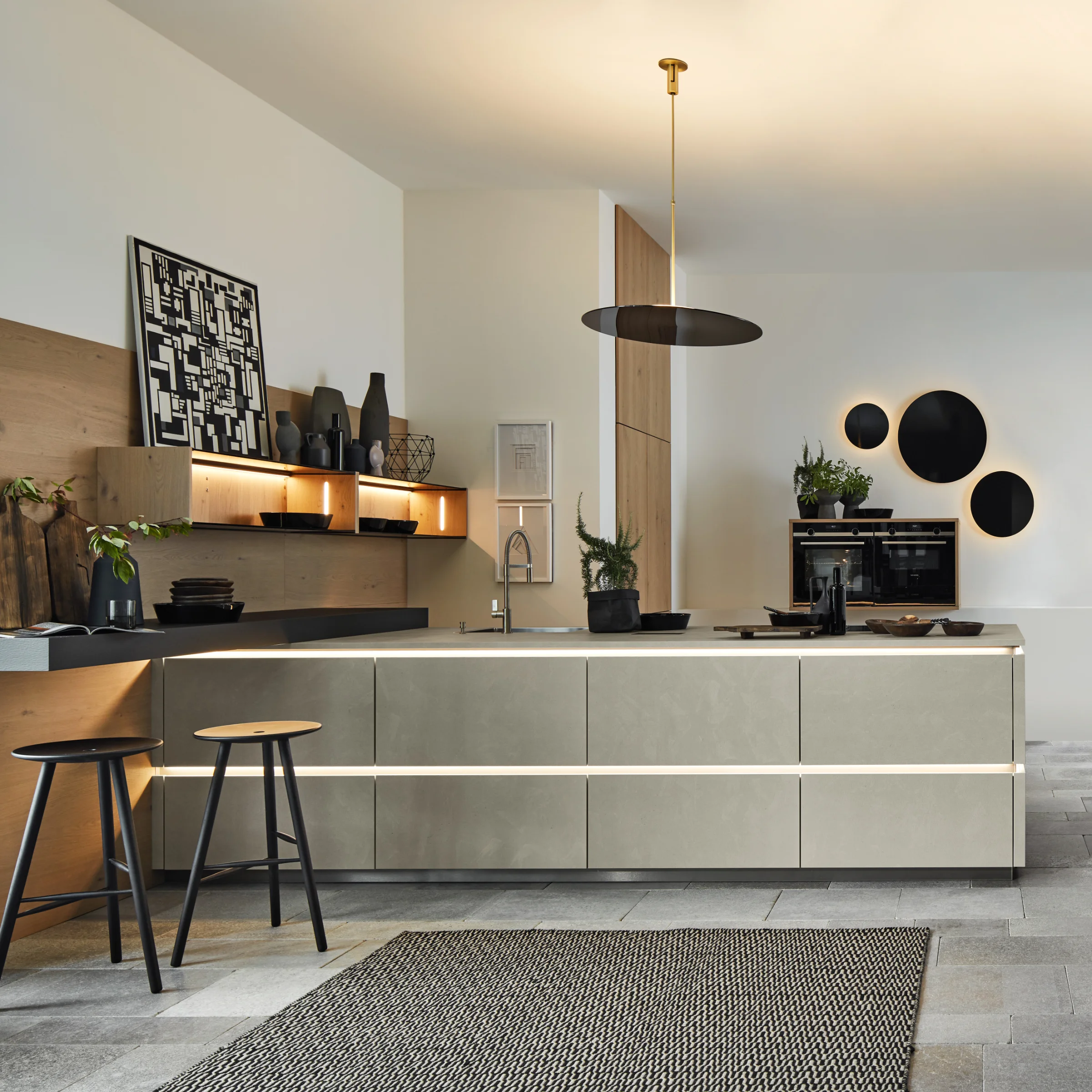 Cucina moderna con isola e sgabelli, decorata con piante e opere d'arte. Nolte Kitchen.