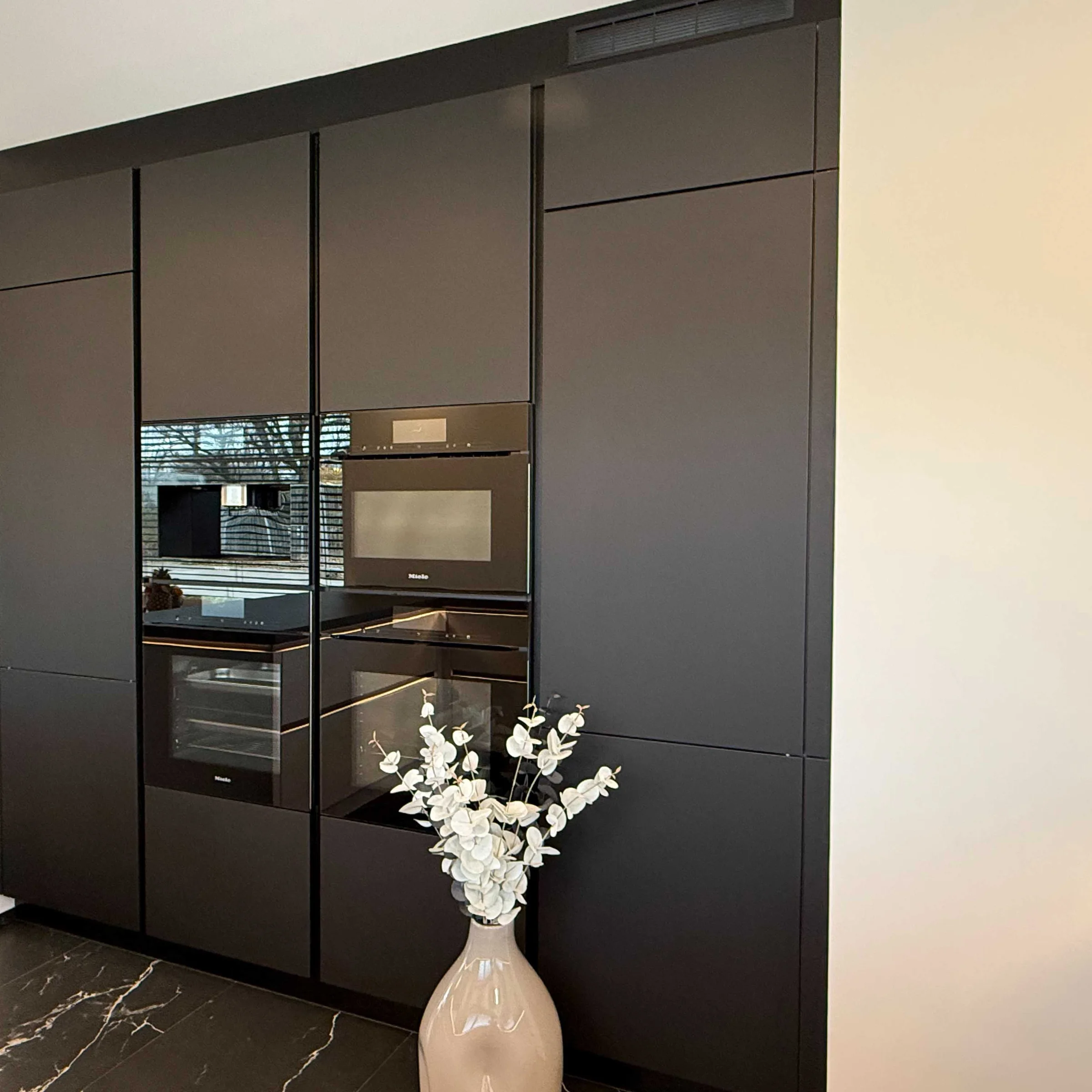 Cucina moderna nera a incasso con bouquet di fiori bianchi, Nolte Kitchen.
