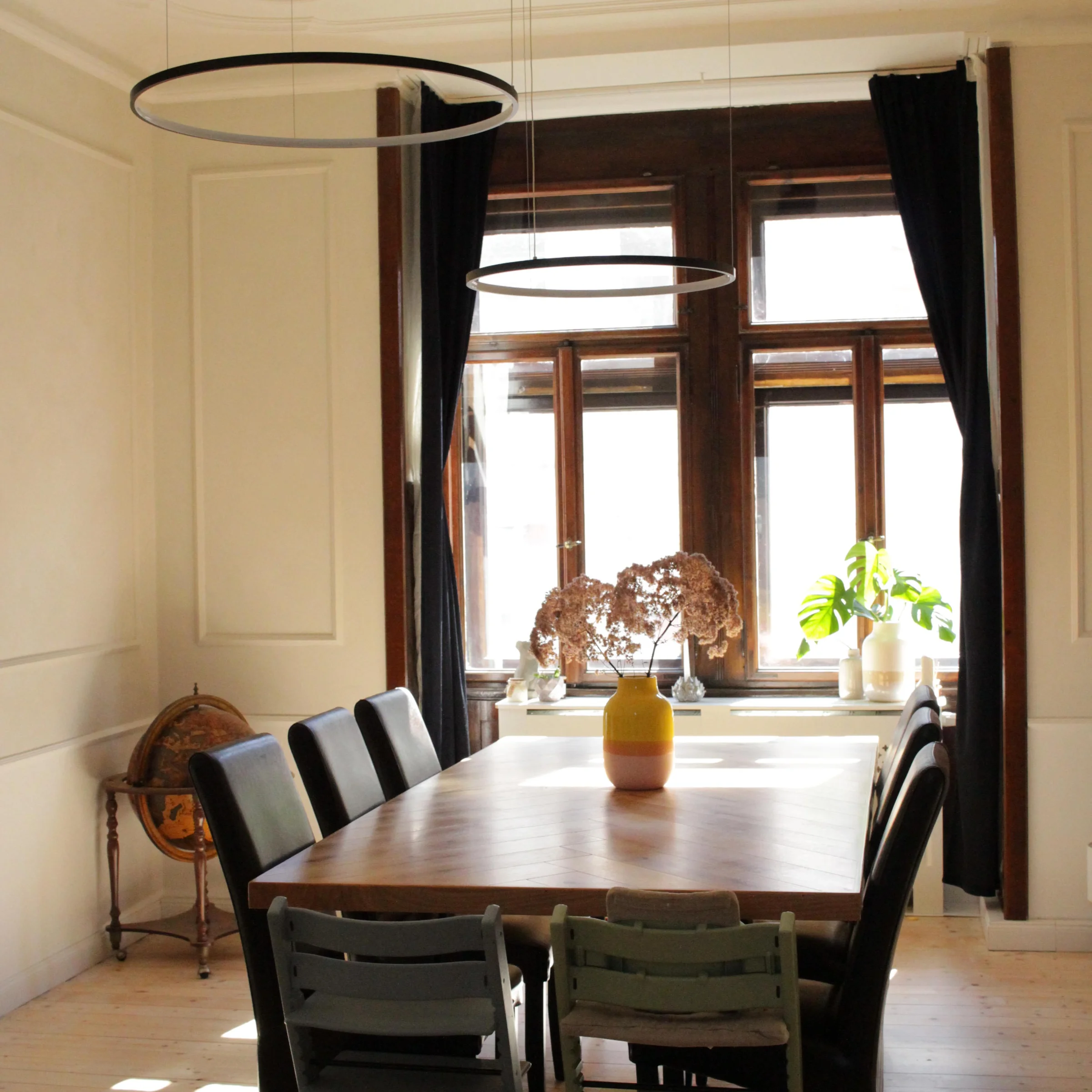 Sala da pranzo con lungo tavolo in legno, sedie e lampade moderne, in stile Nolte Living.