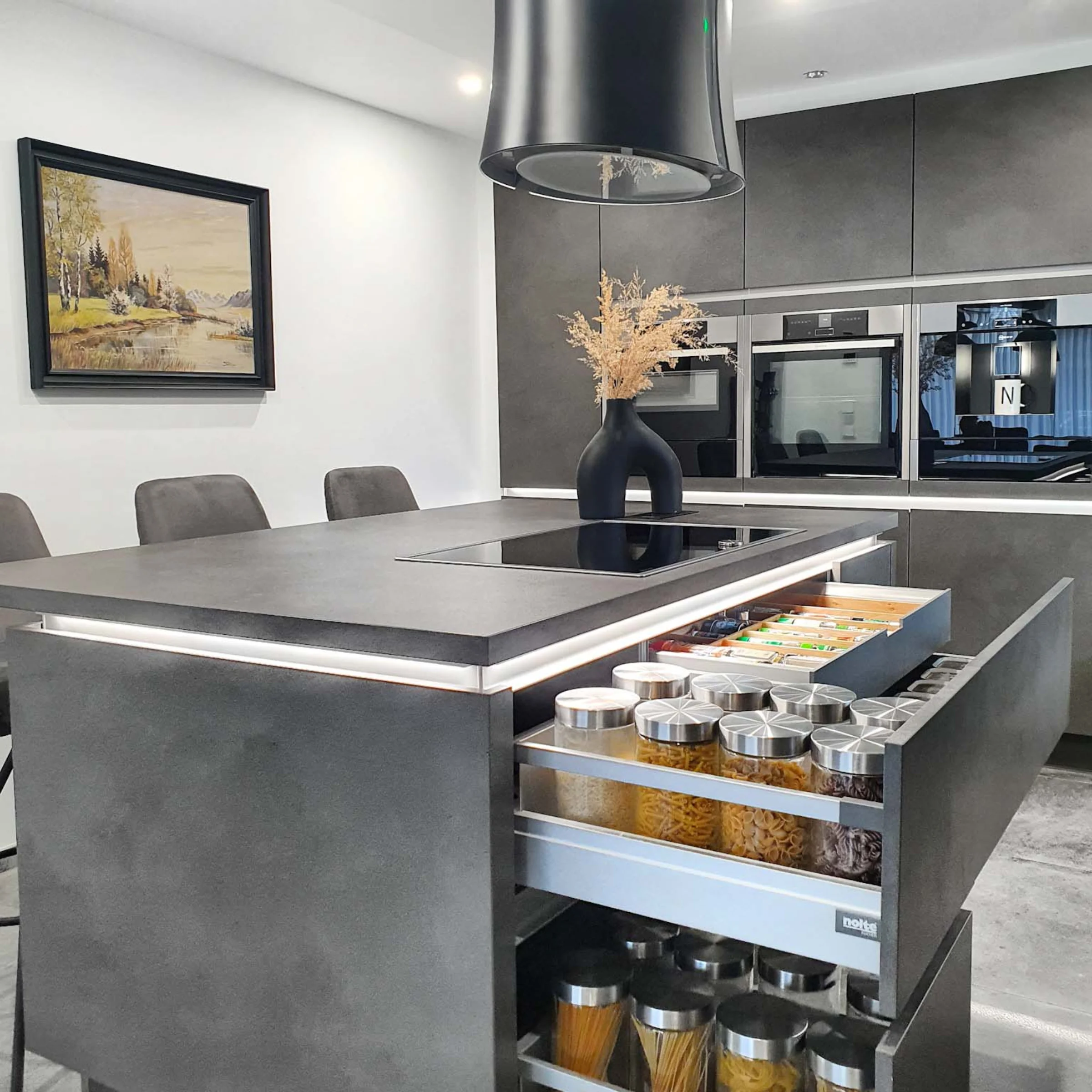 Cucina moderna con armadi grigi e isola, progettata da Nolte Kitchen.