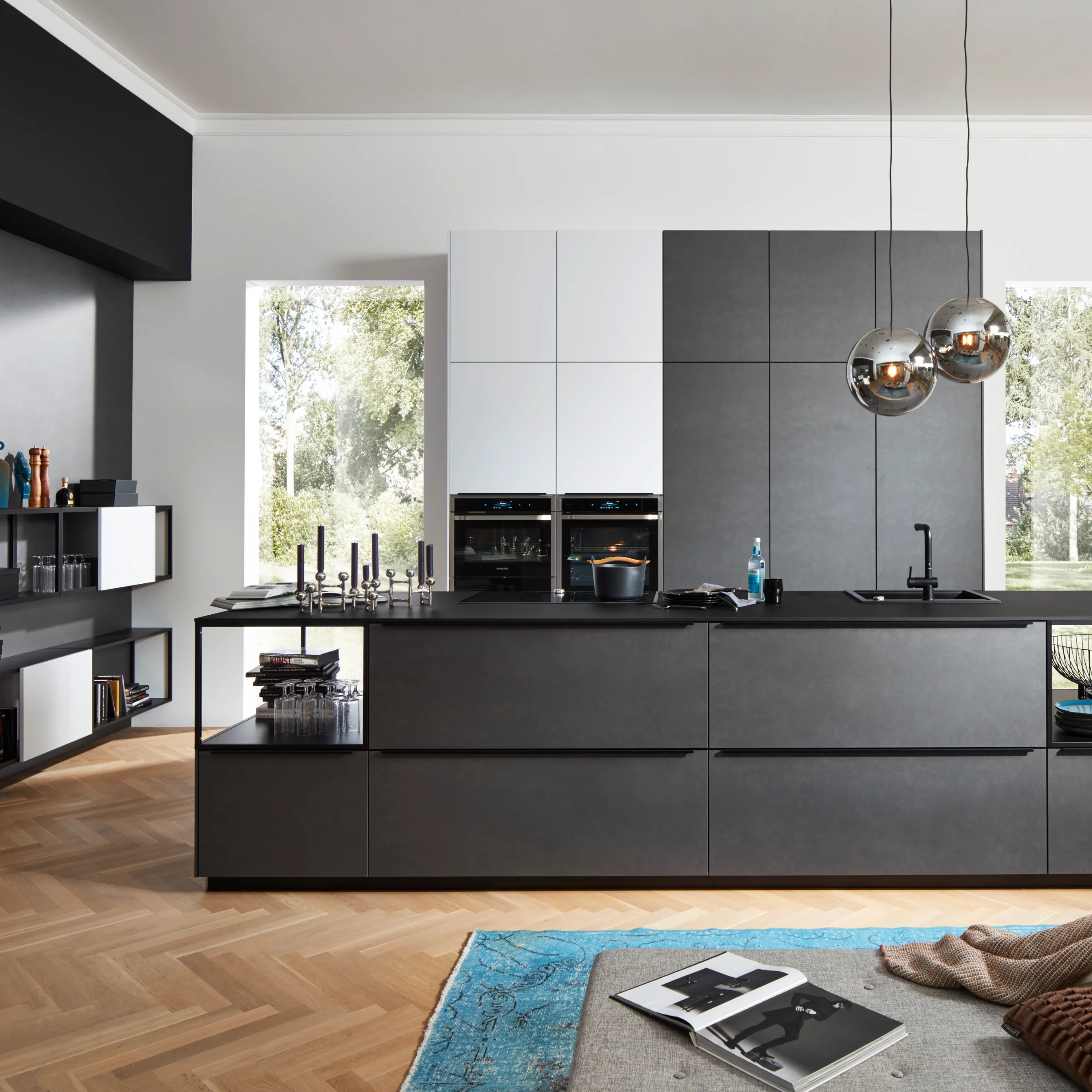 Cucina moderna con isola e mobili neri davanti a grandi finestre, Nolte Kitchen.