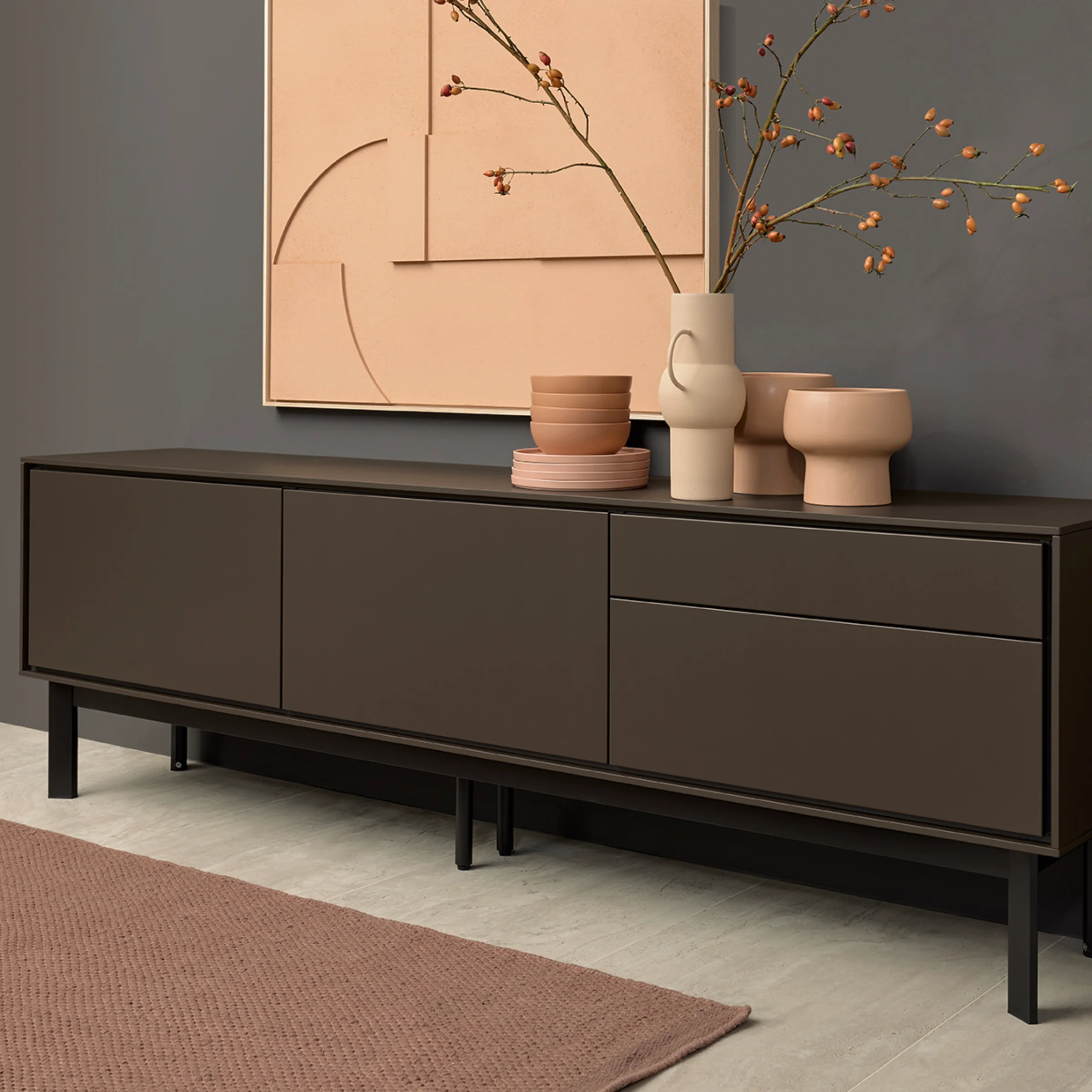 Credenza elegante con vasi davanti a una parete d'arte moderna, presentata da Nolte Living.