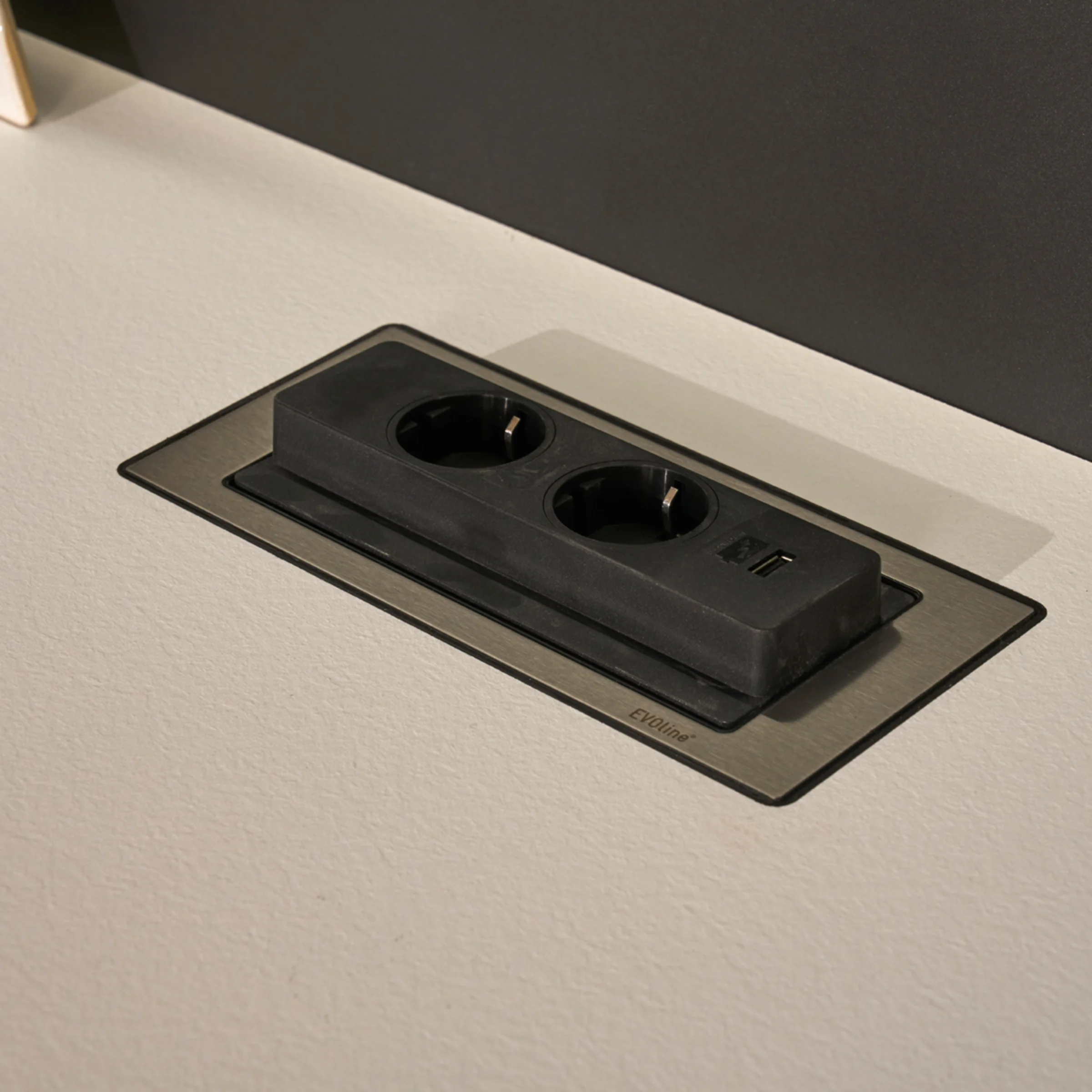 Una presa nera integrata in un piano di lavoro chiaro. Cucine Nolte.
