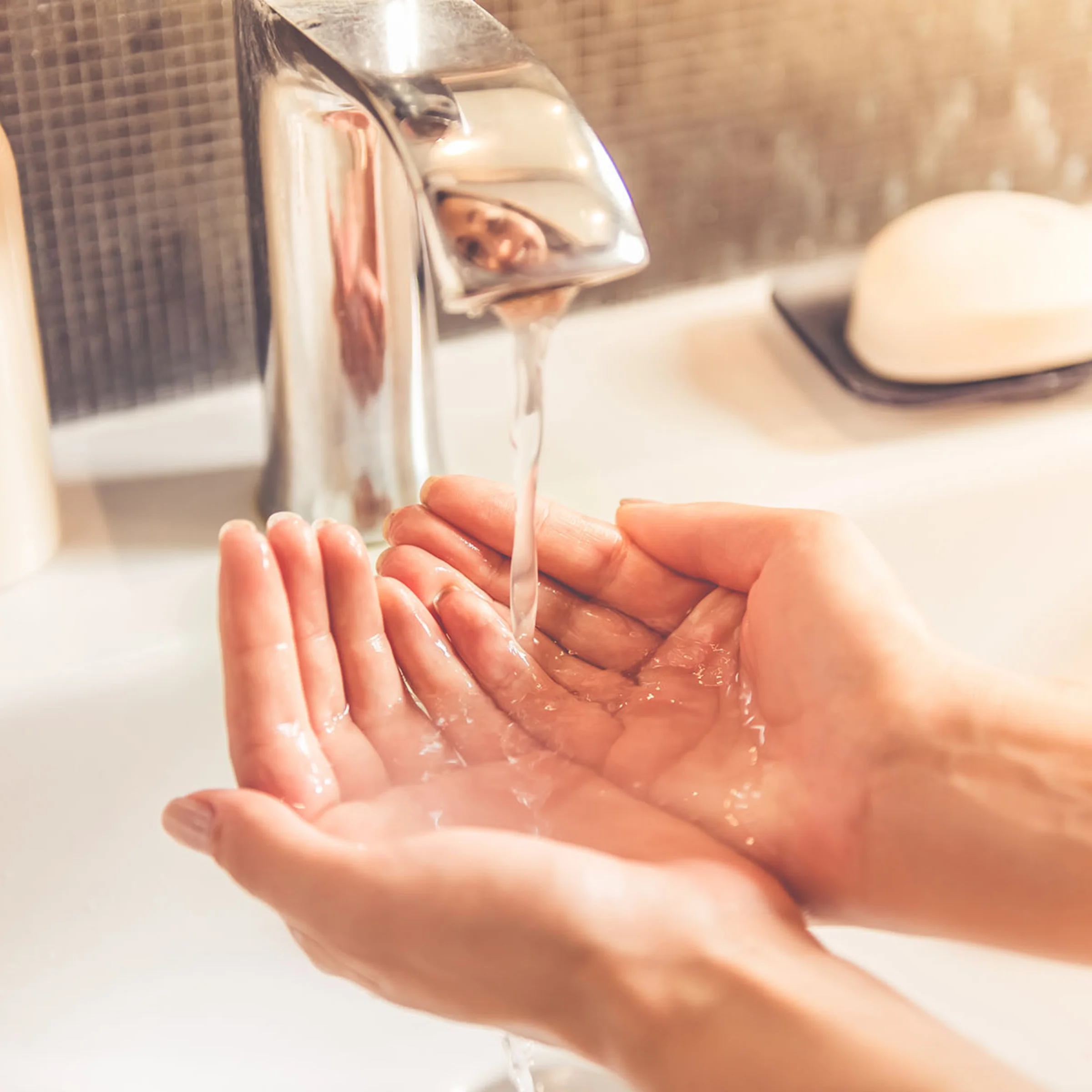 Una persona tiene las manos bajo agua corriente en el baño, Nolte SPA.