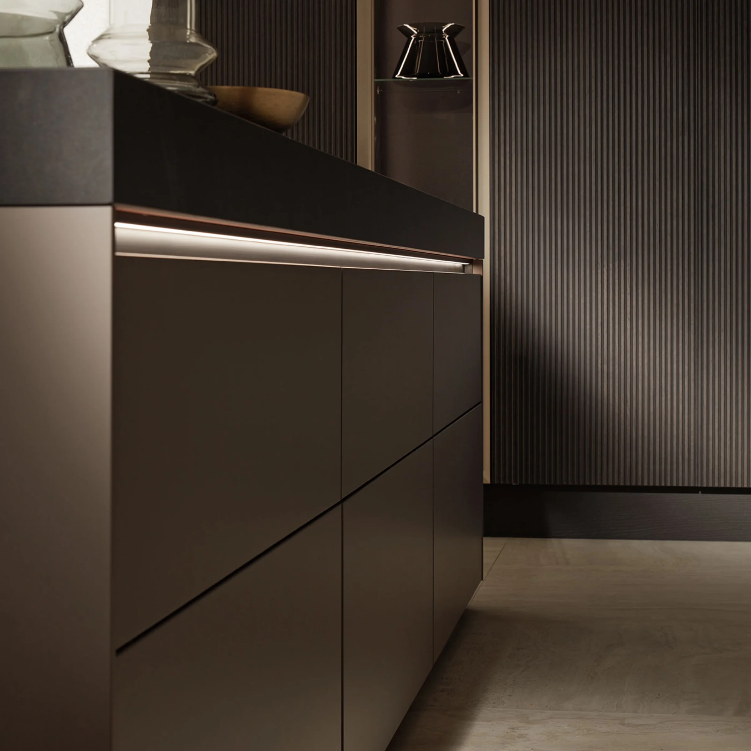Cucina moderna con eleganti armadi scuri e illuminazione di Nolte Kitchen.