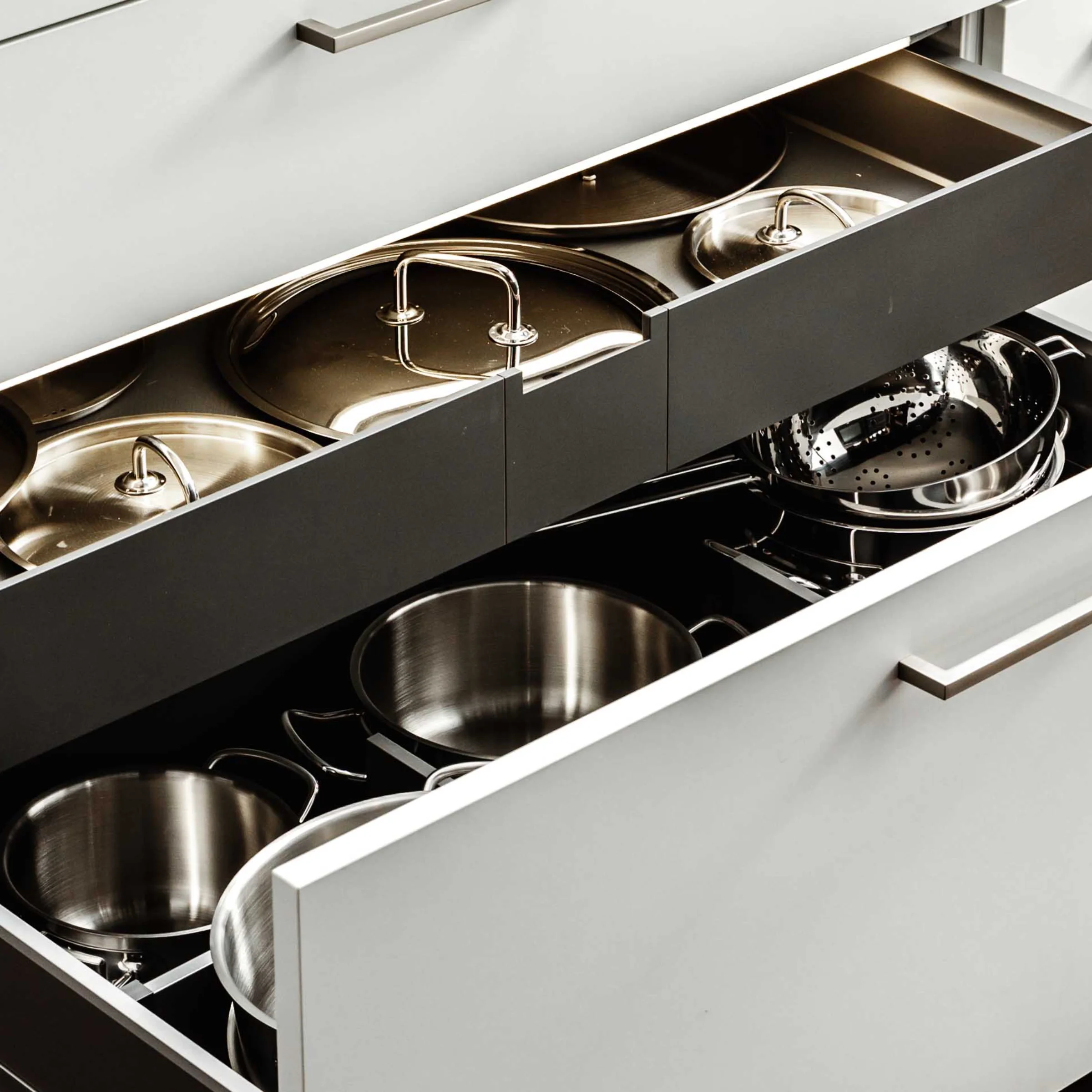 Un armadietto da cucina aperto mostra pentole e padelle dal design moderno di Nolte Kitchen.