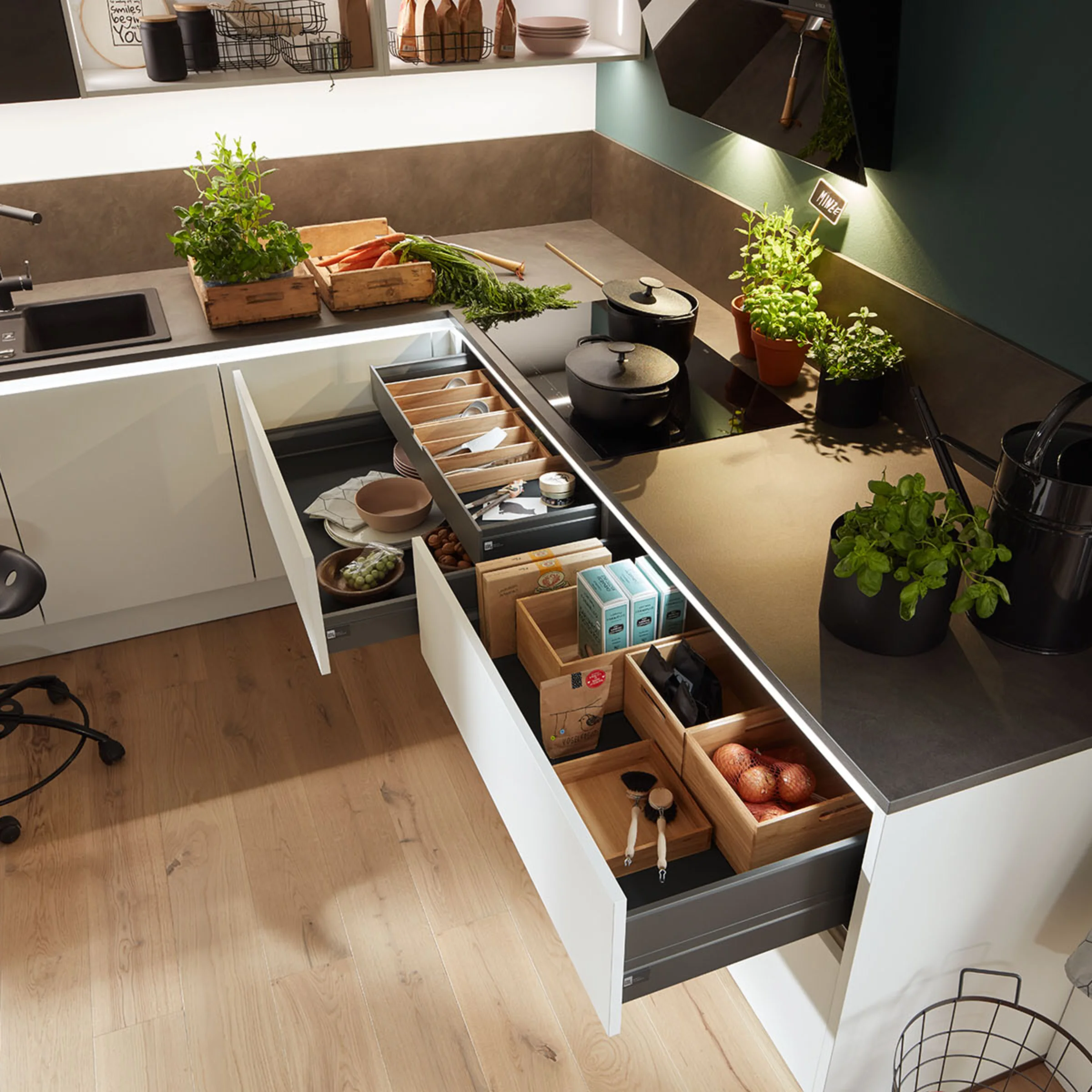 Cucina moderna con cassetti aperti e erbe fresche sul piano di lavoro. Nolte Kitchen.