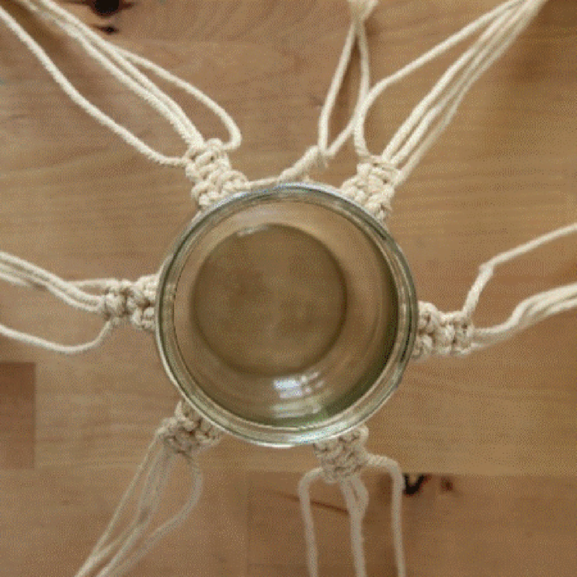 Un vaso di vetro sospeso in una rete macramè, annodata con arte.