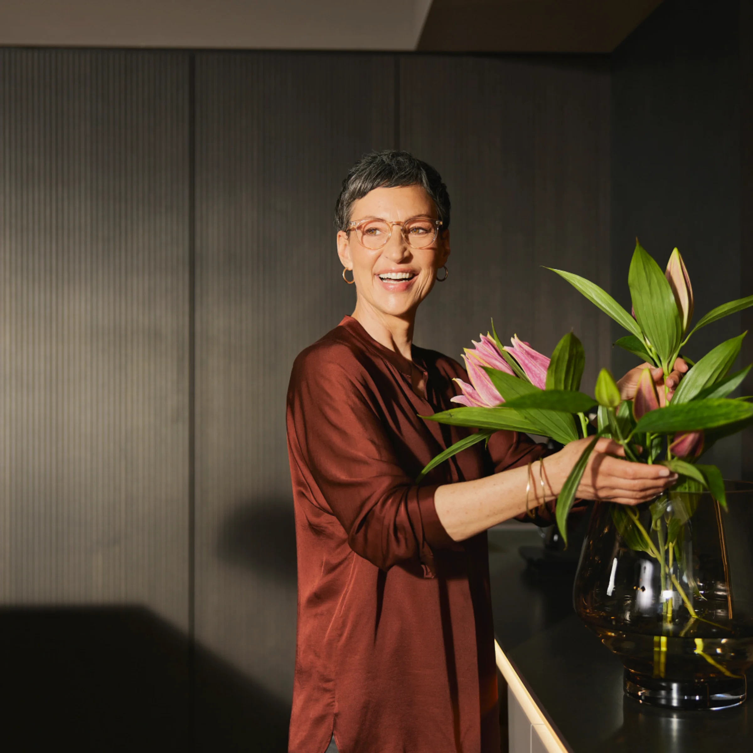 Una donna sistema fiori in una cucina moderna di Nolte Kitchen.