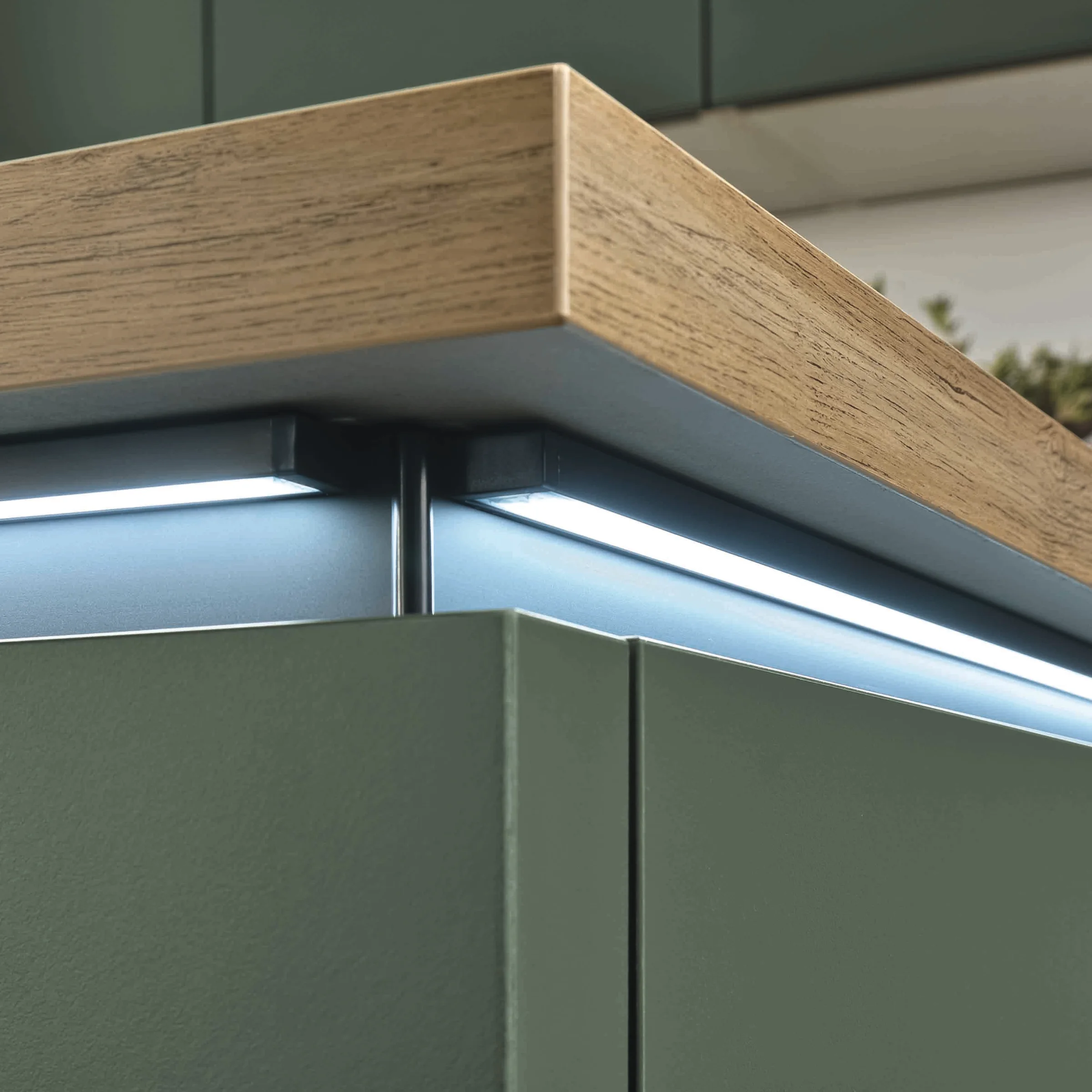 Placards de cuisine verts avec plan de travail en bois et éclairage LED, Express Küchen.
